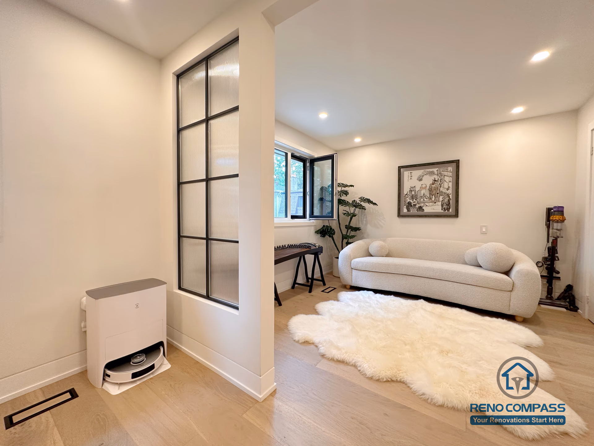 This Toronto interior renovation showcases a modern living area with light hardwood flooring, glass partition detailing, and a clean open-concept layout. The seamless flooring installation enhances continuity between spaces, while soft lighting and refined finishes create a warm, contemporary atmosphere ideal for Toronto home renovations.