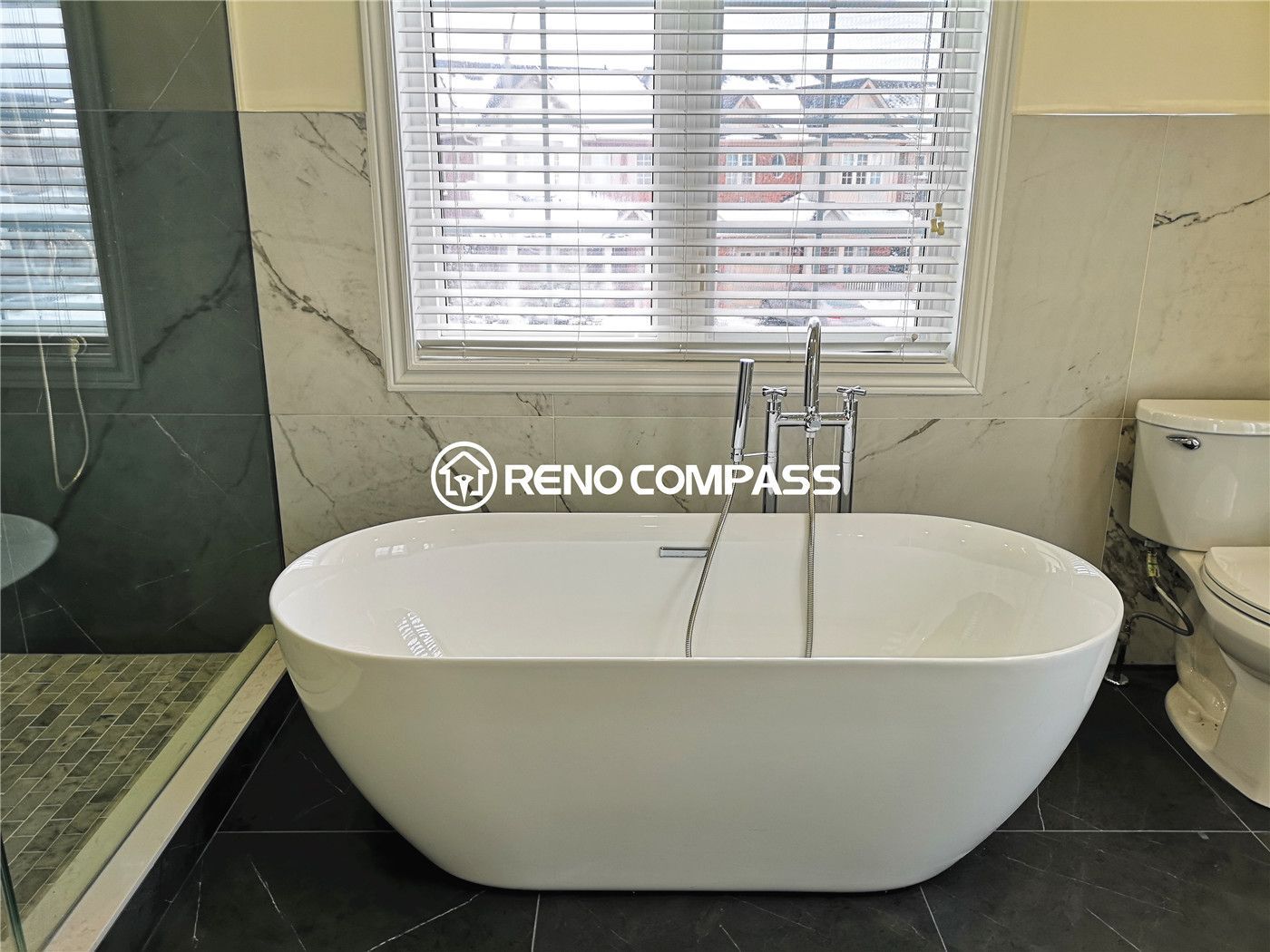 A serene bathroom space featuring a modern freestanding bathtub positioned beneath a large window for natural light. This Richmond Hill renovation by Reno Compass combines elegance and relaxation.