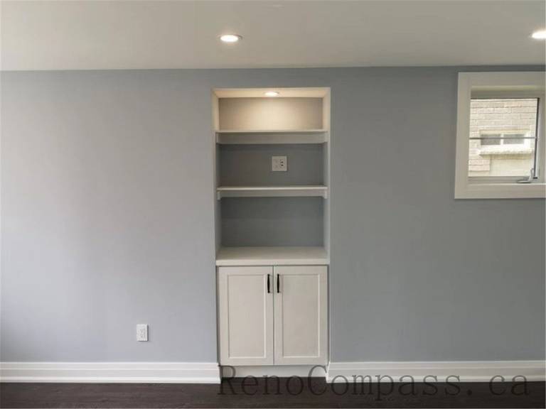 A clean, minimalist basement bathroom renovation showcasing smooth surfaces, recessed lighting, and neutral colors. Reno Compass transformed this Aurora space into a bright, practical area.