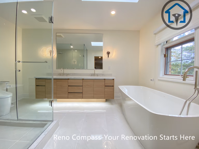 A modern bathroom renovation featuring a freestanding bathtub, glass-enclosed shower, and custom wood vanity with integrated lighting. Designed for a clean, spacious, and functional layout in a Thornhill home by Reno Compass.