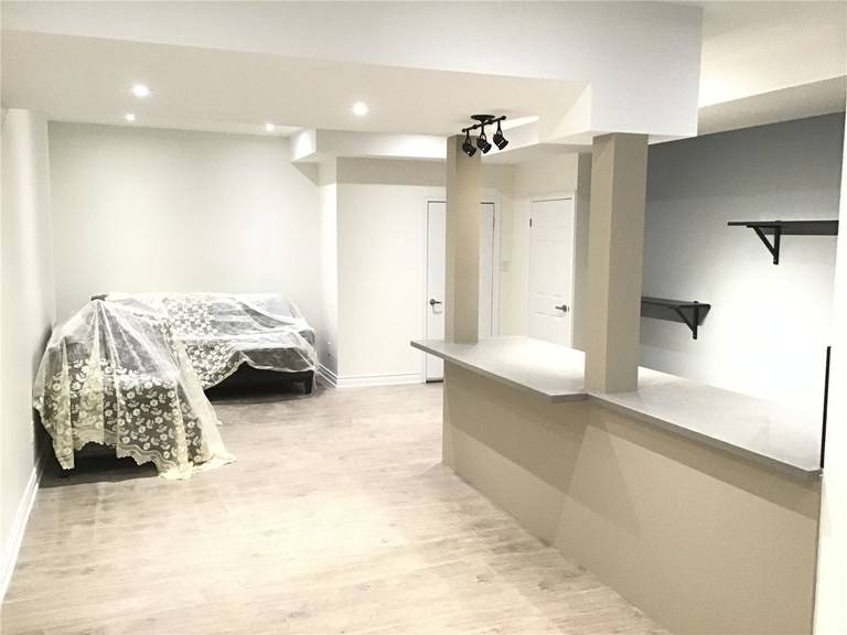 This Aurora basement renovation features a well-designed open concept layout with a custom bar counter, modern lighting, and flexible living space. The layout seamlessly connects different functional areas, making it ideal for entertainment, family use, or conversion into a basement apartment for rental income.