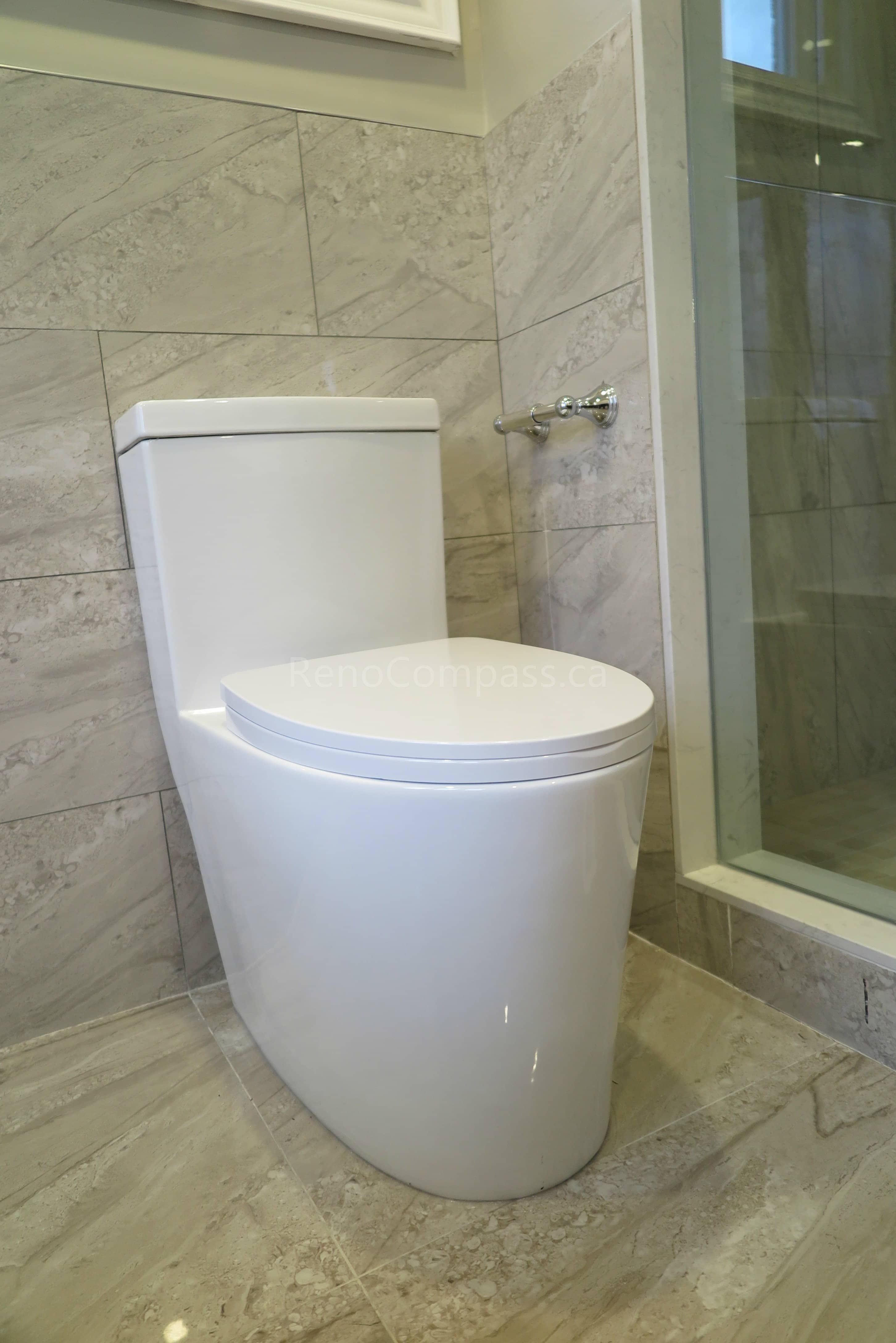 This Markham bathroom renovation features a sleek modern one-piece toilet paired with marble-style wall and floor tiles for a clean and contemporary look. The space includes glass shower enclosure detailing and high-quality tile installation that enhances durability and easy maintenance. Completed by Reno Compass, a professional renovation contractor specializing in bathroom renovations, tile installation, and full interior remodeling across Markham and the Greater Toronto Area.