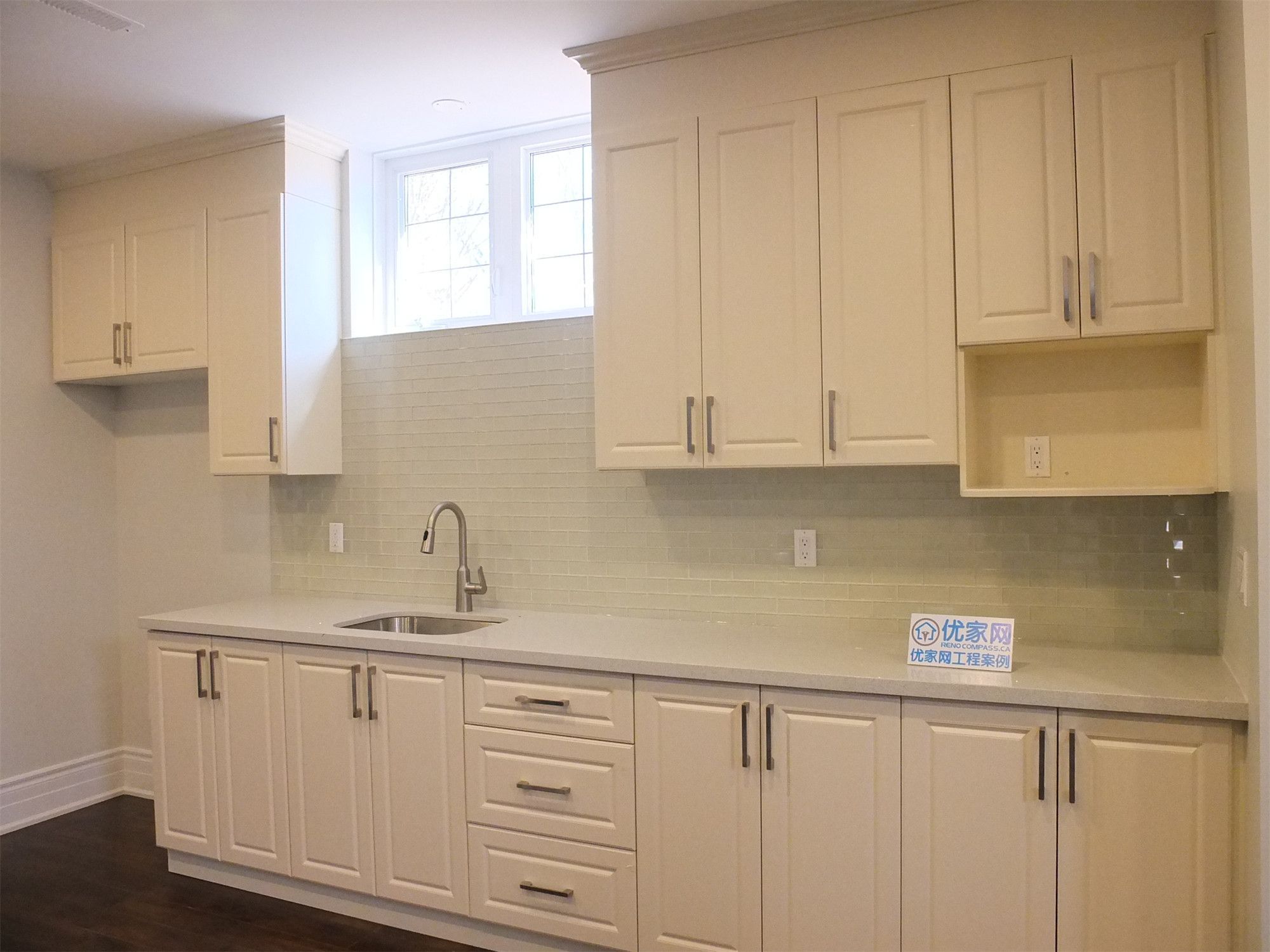 This Richmond Hill basement renovation includes a beautifully finished kitchen area featuring custom cream cabinetry, quartz countertops, and a modern tile backsplash. The space is designed with ample storage, a functional sink station, and clean upper and lower cabinets for a sleek and organized look. Bright basement windows and neutral finishes enhance the overall atmosphere, creating a practical and stylish secondary kitchen ideal for rental or multi-generational living.