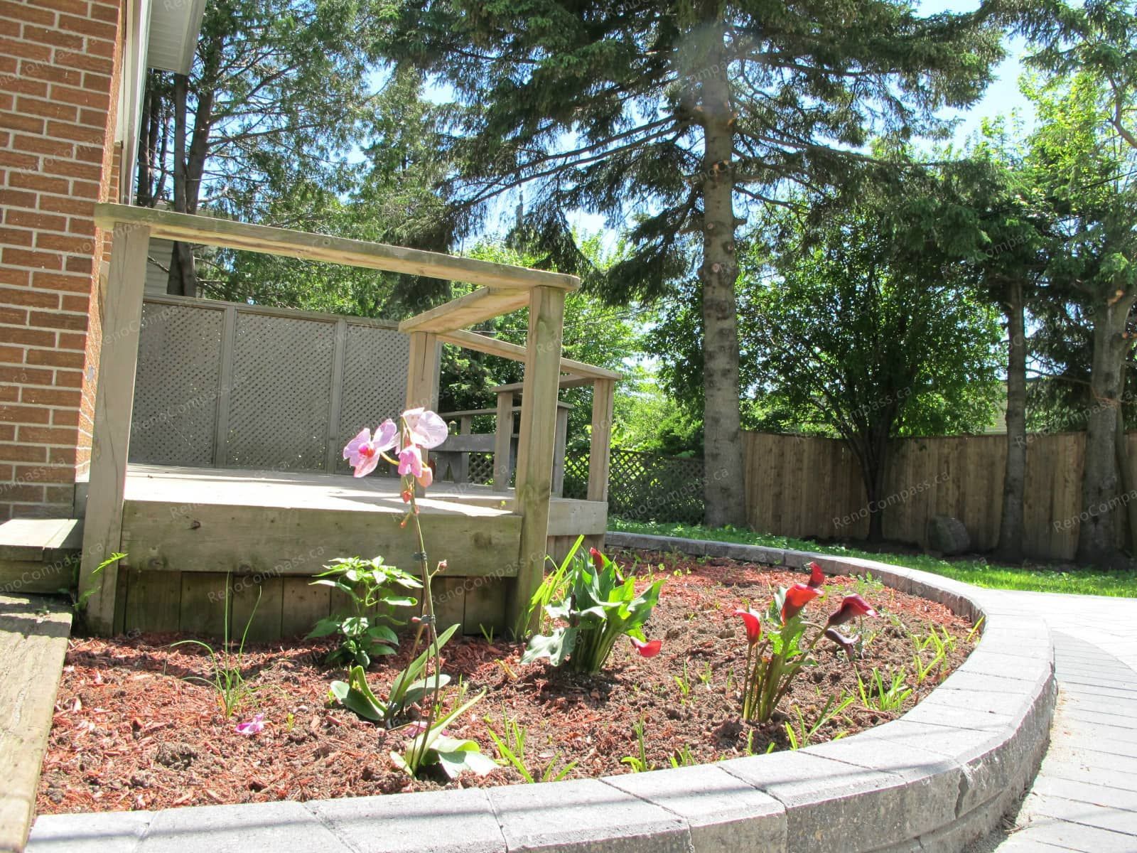 This Markham landscaping project showcases a custom-built garden bed constructed with durable interlock stone. The curved interlock edging creates a clean and structured flower bed layout while enhancing the overall backyard design. Filled with fresh mulch and ready for planting, the raised flower bed adds depth and visual interest to the outdoor space. Completed by Reno Compass Inc., this project highlights professional craftsmanship in interlock landscaping and garden design, delivering a low-maintenance and elegant outdoor environment for homeowners.