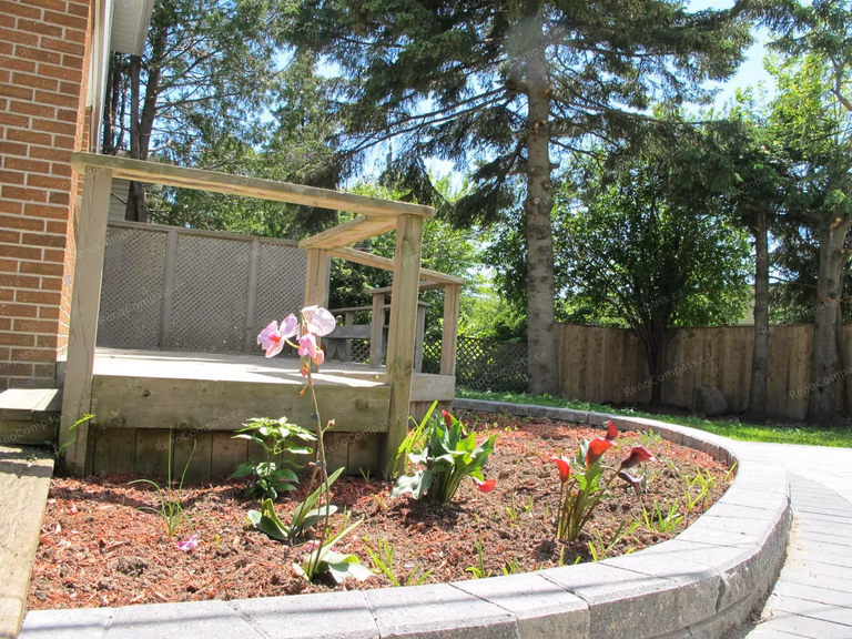 This Markham landscaping project showcases a custom-built garden bed constructed with durable interlock stone. The curved interlock edging creates a clean and structured flower bed layout while enhancing the overall backyard design. Filled with fresh mulch and ready for planting, the raised flower bed adds depth and visual interest to the outdoor space. Completed by Reno Compass Inc., this project highlights professional craftsmanship in interlock landscaping and garden design, delivering a low-maintenance and elegant outdoor environment for homeowners.