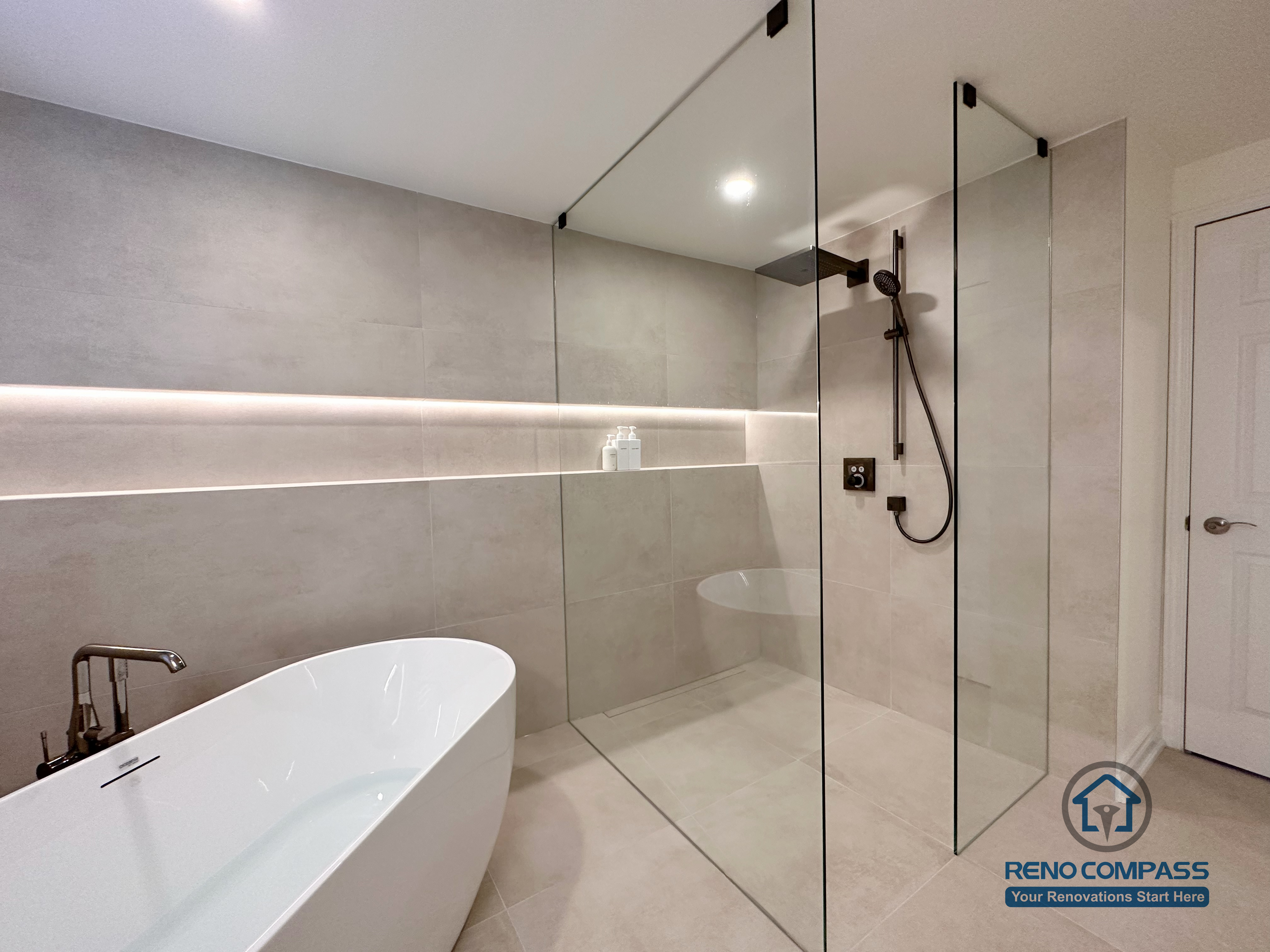 This Markham accessible bathroom renovation features a barrier-free walk-in shower with a clear glass panel, large-format tile flooring, and a freestanding bathtub for comfortable, step-free access. Integrated linear lighting and slip-resistant surfaces enhance safety while maintaining a clean, modern appearance. Designed and built by a professional Toronto renovation company, Reno Compass Inc., the space balances accessibility, functionality, and refined design.
