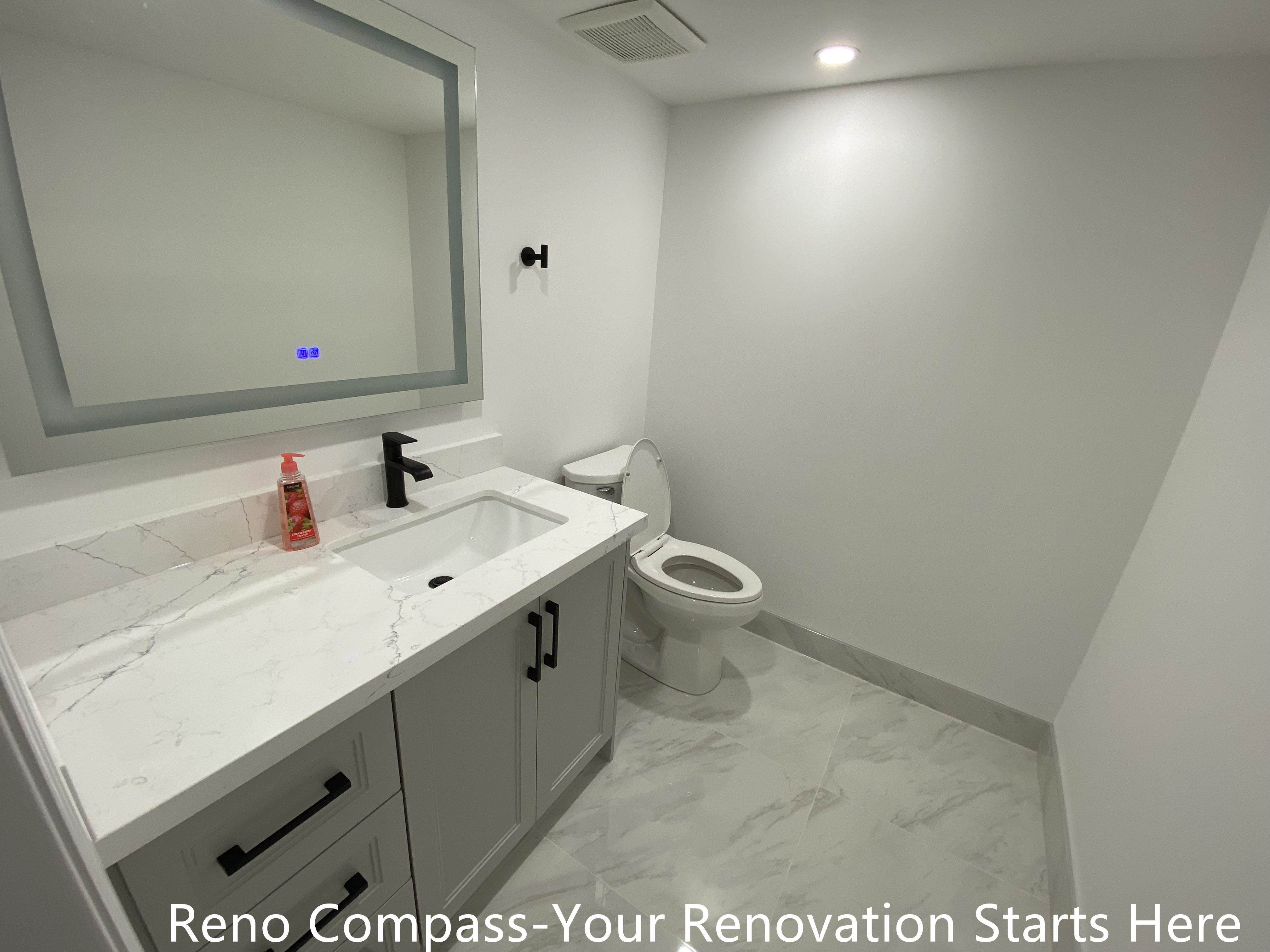 This basement bathroom renovation in Bradford features a clean, modern design focused on durability and everyday functionality. The space is finished with large-format marble-look floor tiles that visually expand the room while improving moisture resistance and ease of maintenance. A custom vanity with flat-panel cabinetry provides practical storage, paired with a quartz countertop and an undermount sink for a seamless, low-maintenance surface. Matte black fixtures and hardware add contrast and definition, creating a balanced and contemporary basement bathroom suitable for guest use or rental living. Designed and built as part of a complete Bradford basement renovation by Reno Compass Inc., this bathroom reflects careful planning, precise detailing, and long-term usability.