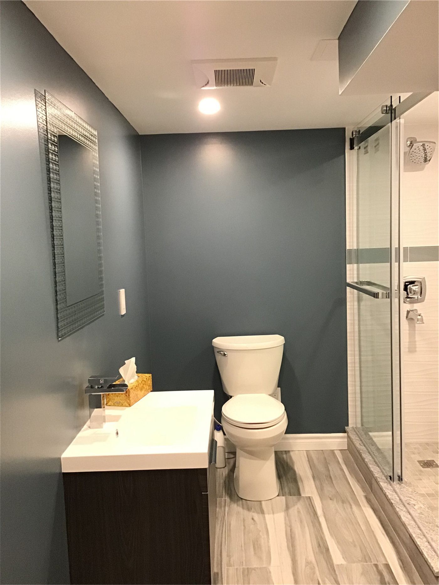Fully finished basement bathroom completed in this Richmond Hill basement renovation. Featuring a modern floating vanity, glass-enclosed shower, textured tile walls, and durable vinyl plank flooring, this thoughtfully designed space maximizes functionality while maintaining a clean, contemporary aesthetic.