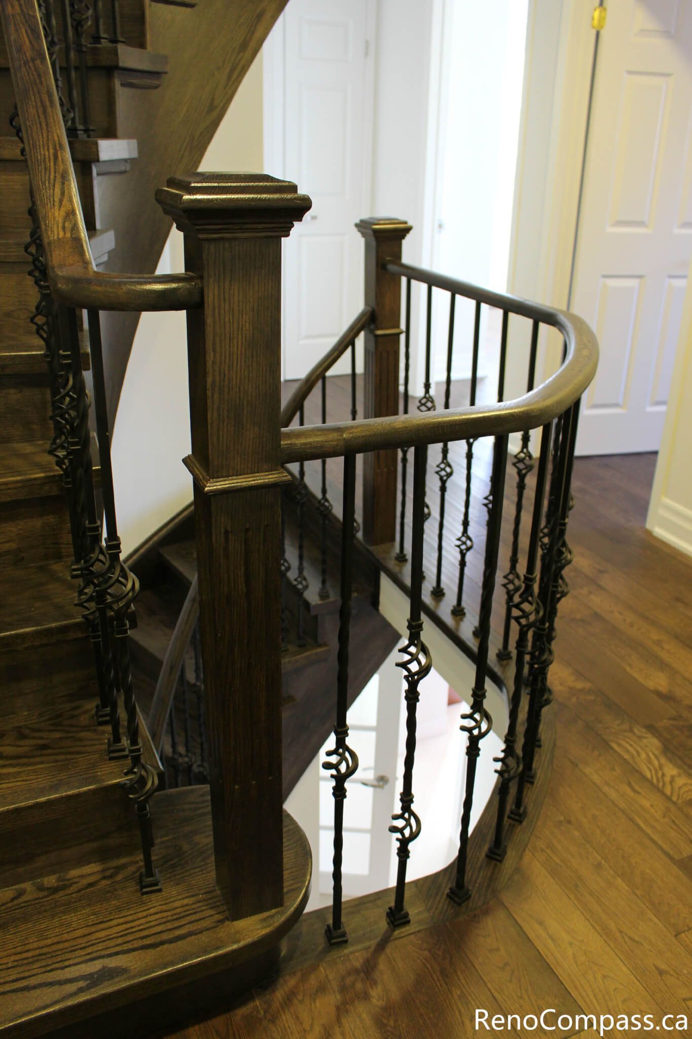 This Mississauga interior renovation showcases a custom curved iron stair railing paired with rich hardwood flooring and clean modern wall finishes. The detailed railing design enhances both safety and architectural elegance, creating a refined open stairwell feature. Completed by a trusted Toronto renovation company, Reno Compass Inc., this project highlights precision craftsmanship and high-quality interior finishing.