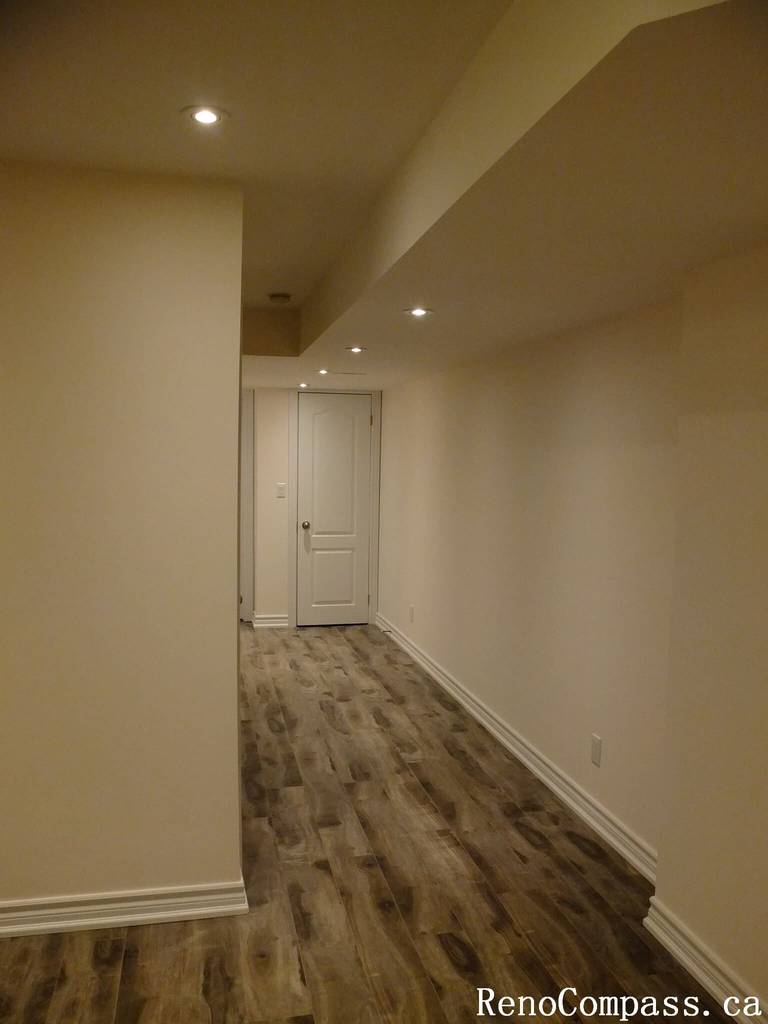 This Markham basement renovation features a clean and modern hallway design with recessed pot lights, durable wood-look vinyl flooring, and neutral wall finishes. The updated layout enhances brightness and flow, creating a functional and inviting basement space for homeowners in Markham.