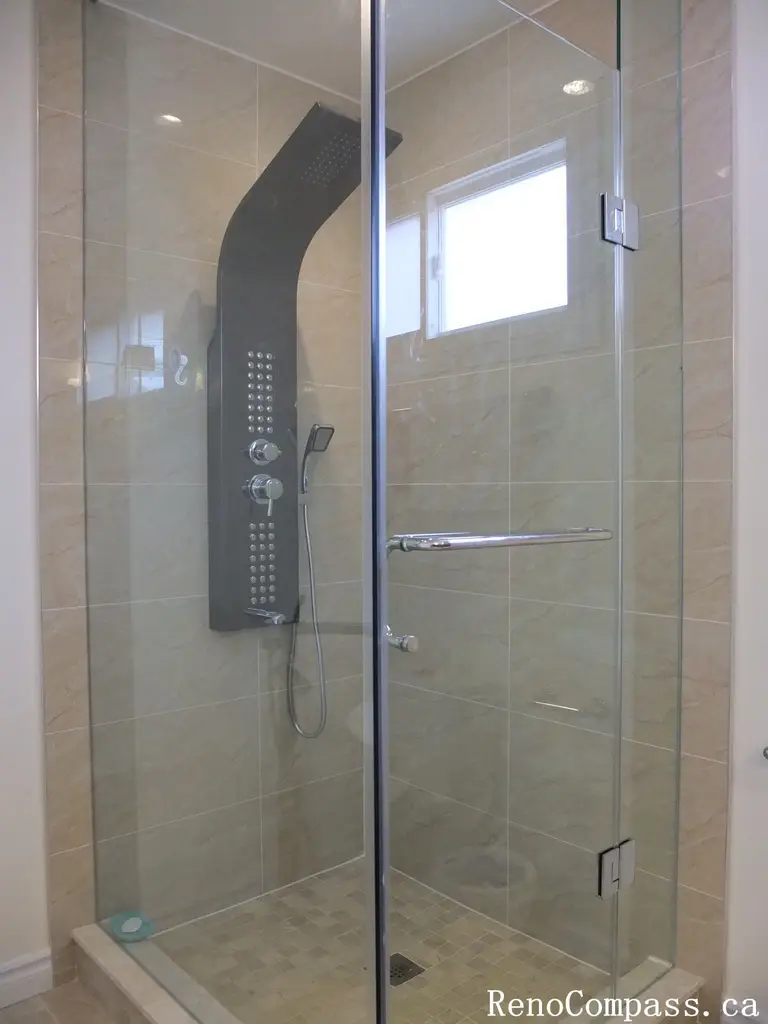 Interior bathroom renovation in North York featuring a frameless glass shower, full-body rain shower system, and large-format porcelain wall tiles. This Toronto interior renovation focuses on modern functionality, clean detailing, and efficient use of space for everyday comfort.