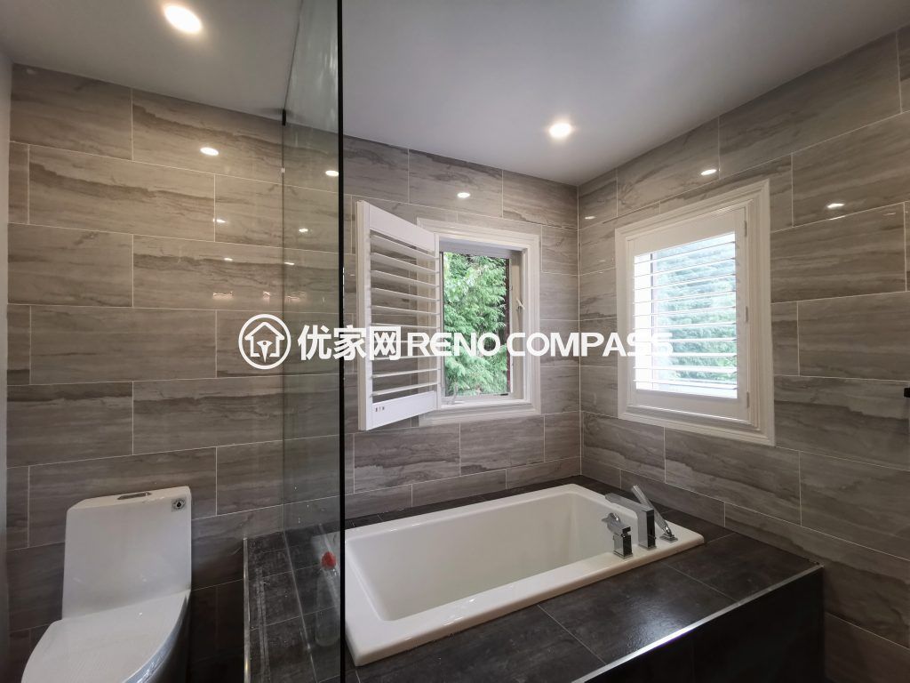 Modern bathroom interior renovation in Richmond Hill featuring a built-in bathtub, frameless glass shower enclosure, large format wall tiles, and contemporary fixtures. This interior renovation showcases clean lines, improved natural lighting, and functional layout design by a professional Toronto renovation team.