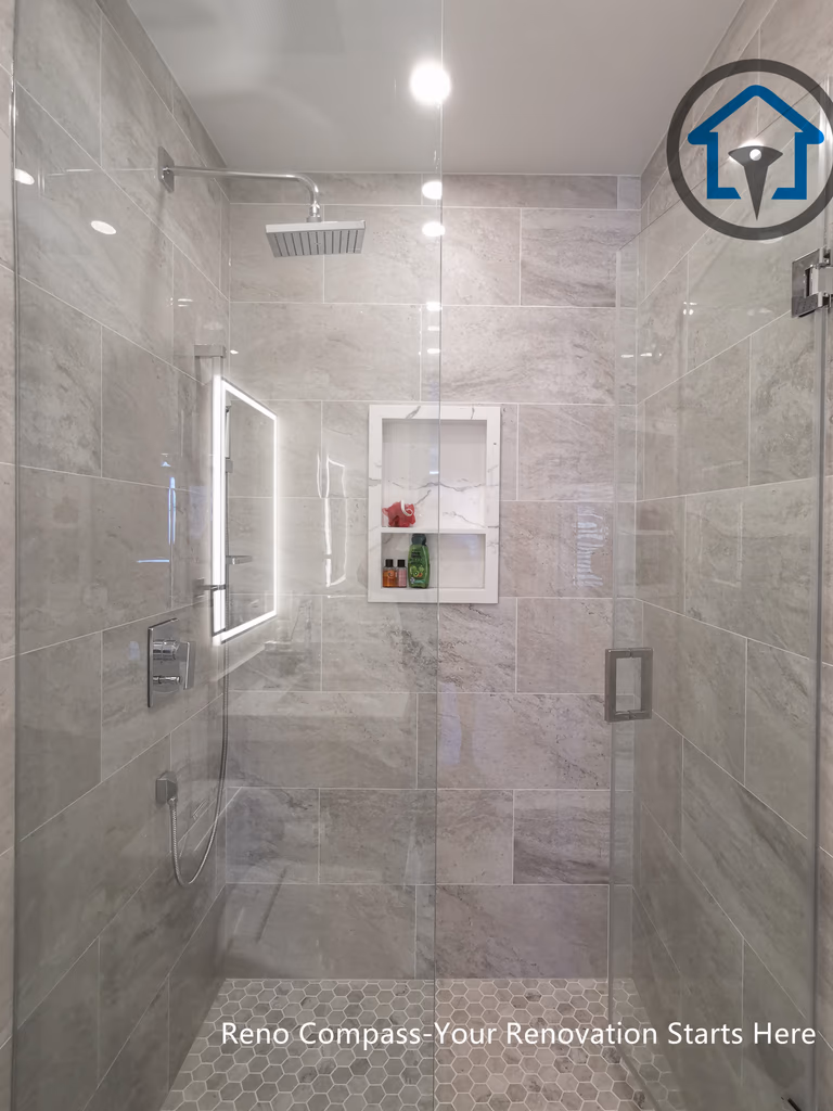 This North York bathroom renovation features a modern floating-style vanity paired with a quartz countertop and a glass-enclosed shower. Neutral wall tiles, built-in shower storage, and LED mirror lighting create a clean and functional layout that maximizes space and comfort. Completed by a Toronto renovation company focused on efficient bathroom design and quality craftsmanship.