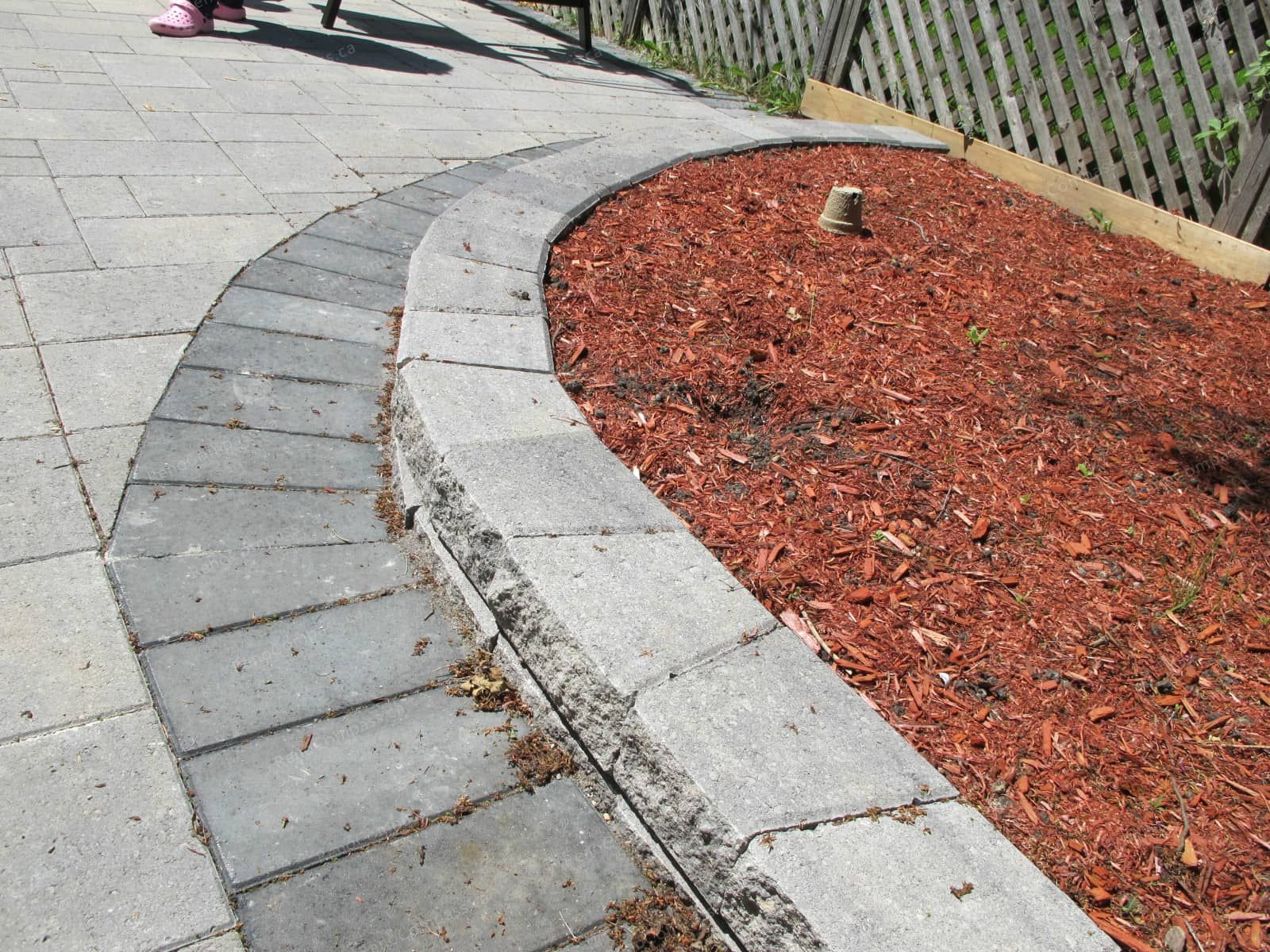 This Markham backyard landscaping project features a professionally installed interlock walkway with curved stone borders and a raised garden bed design. The combination of durable paving stones and clean edging creates a neat, modern outdoor layout that enhances both functionality and visual appeal. Completed by Reno Compass Inc., this project demonstrates expert craftsmanship in interlock installation and garden landscaping, providing homeowners with a low-maintenance and stylish outdoor environment.