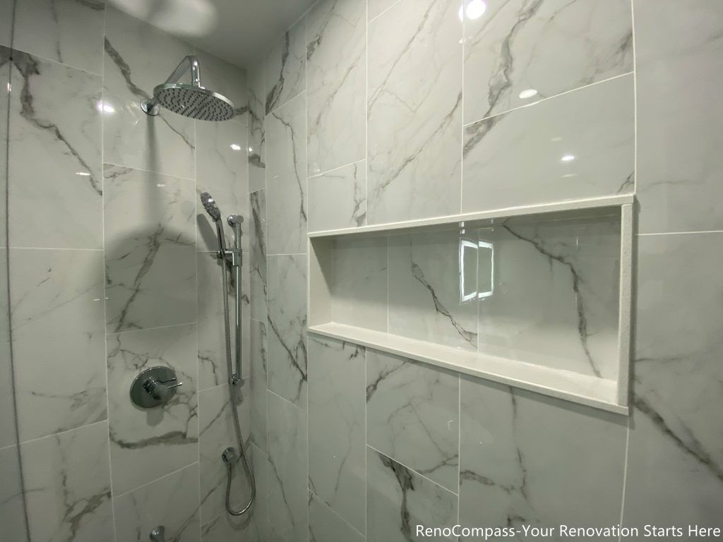 This Oakville bathroom renovation features a modern walk-in shower with large-format marble-look tiles, a built-in recessed shower niche, and a sleek rainfall shower system. The clean tile layout and contemporary fixtures create a bright, spa-inspired shower space that combines style with practicality. Completed by a trusted Toronto renovation company, this upgrade focuses on waterproofing quality, durable materials, and functional storage solutions to deliver a modern bathroom designed for comfort and long-term performance.