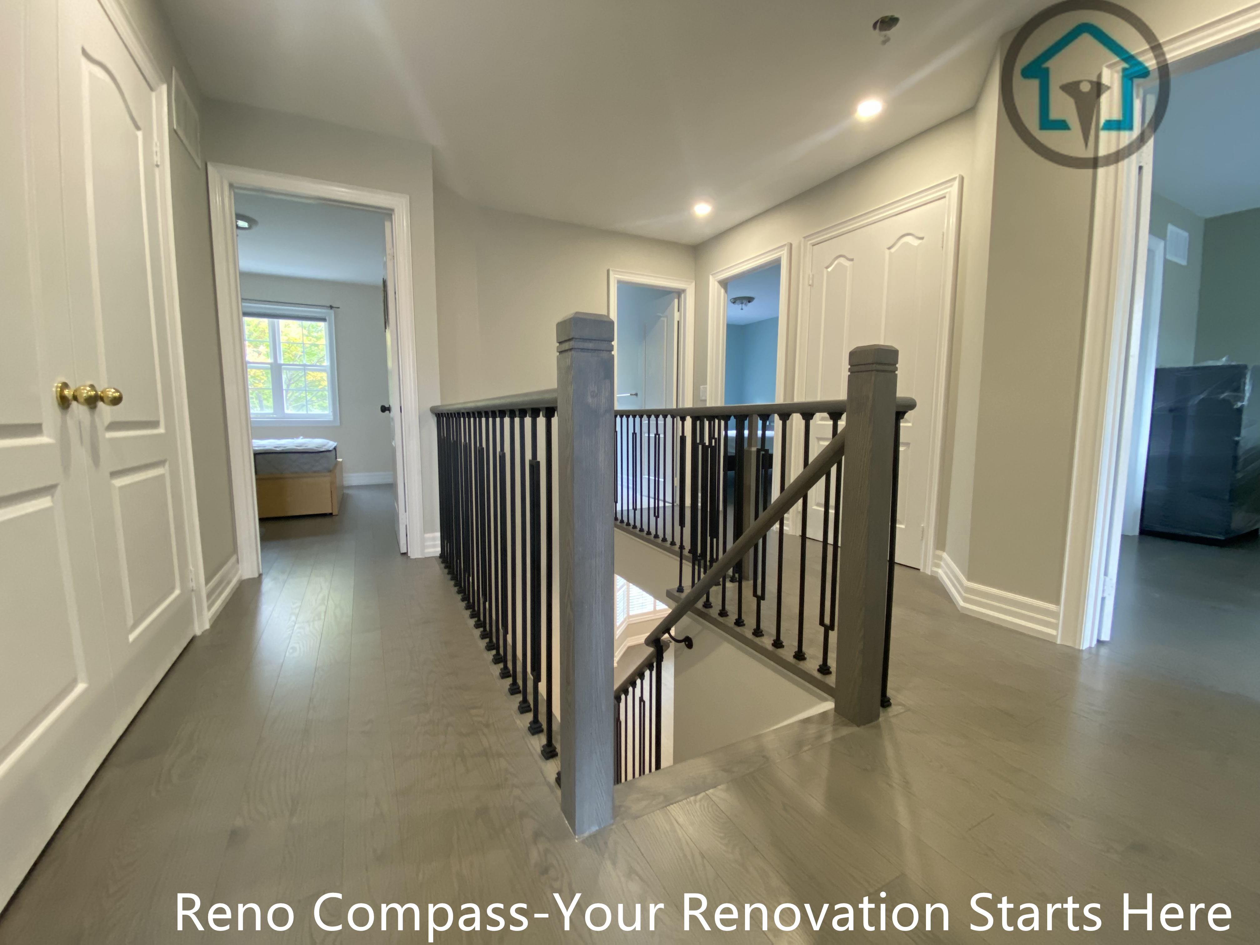 This second-floor hallway renovation features wide-plank flooring, recessed ceiling lighting, and a custom stair guardrail with wood posts and slim black metal balusters. The design enhances safety while maintaining openness and clear sightlines between levels. Neutral finishes and consistent detailing create a calm, cohesive transition between bedrooms and the stairwell, completed as part of a full interior renovation by Reno Compass.