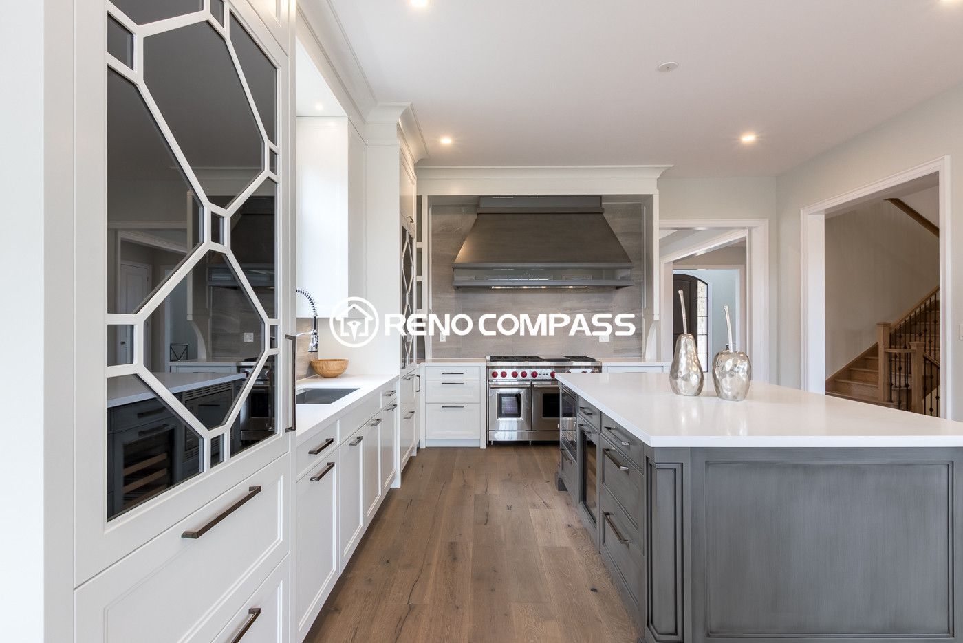 Modern open concept kitchen renovation in Newmarket featuring a large kitchen island, custom cabinetry, recessed pot lights, and engineered hardwood flooring. This bright interior renovation creates a seamless connection between the kitchen, dining, and living space for a spacious and elegant home design.