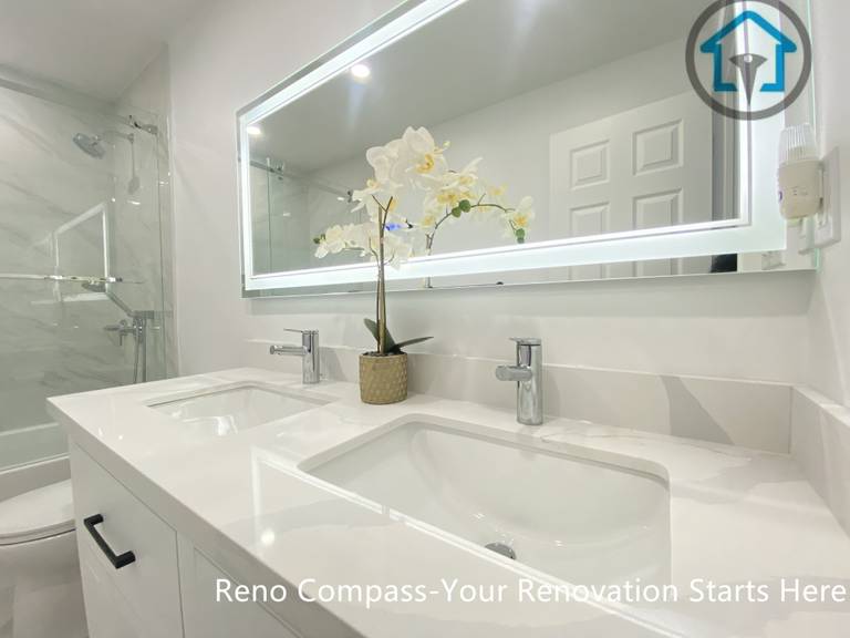 This Pickering bathroom renovation features a clean, modern double-sink vanity designed for everyday convenience and visual balance. The seamless white countertop, integrated rectangular sinks, and minimalist chrome faucets create a calm and refined look. A full-width LED mirror enhances lighting and depth, improving both functionality and the overall bathroom experience.