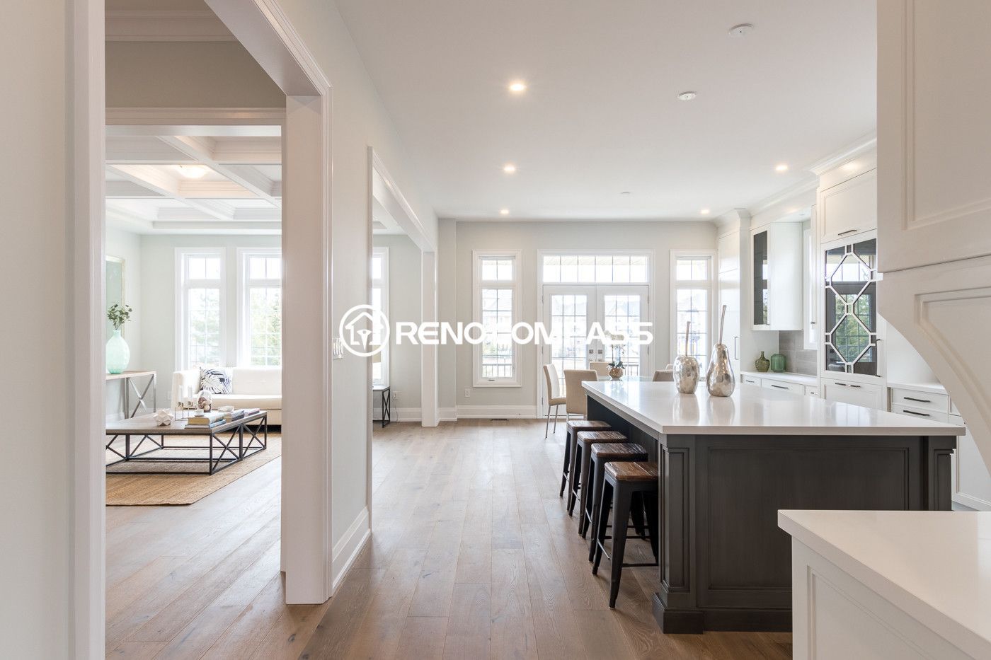 Modern open concept kitchen renovation in Newmarket featuring a large kitchen island, custom cabinetry, recessed pot lights, and engineered hardwood flooring. This bright interior renovation creates a seamless connection between the kitchen, dining, and living space for a spacious and elegant home design.