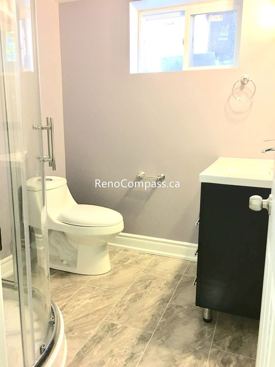 This Toronto basement renovation features a newly finished bathroom with a modern glass shower enclosure, sleek toilet installation, and durable stone-look tile flooring and walls. The clean layout and neutral tones create a bright, functional, and contemporary basement bathroom. Completed by a professional Toronto renovation company, this upgrade enhances comfort, usability, and overall property value with quality craftsmanship and practical design.