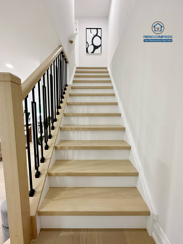 This Richmond Hill interior renovation features a modern hardwood staircase with natural wood treads, white risers, and black metal balusters. The clean lines and light-toned finishes enhance brightness and visual flow between floors. Completed by a Toronto renovation company, the staircase adds both safety and contemporary style to the home.