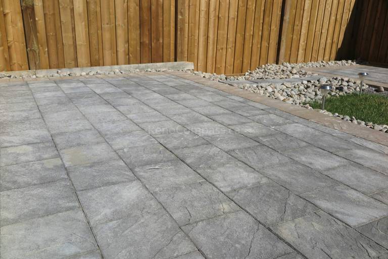 Spacious backyard interlocking patio completed in Aurora featuring modern grey stone pavers, clean linear layout, and decorative gravel border along the wooden fence. This professional landscaping and paving project creates a durable, low-maintenance outdoor space ideal for entertaining and everyday use. Installed by Reno Compass Inc., a trusted Toronto renovation and landscaping contractor serving Aurora and surrounding GTA areas.
