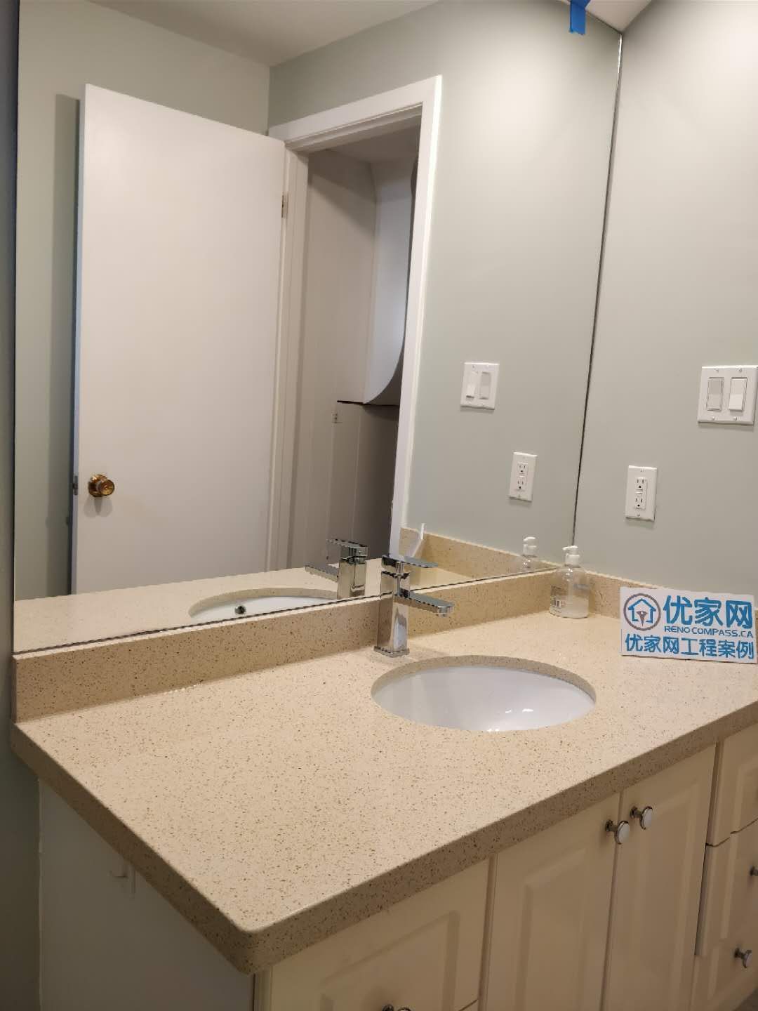 Modern bathroom vanity installed during a Scarborough interior renovation project. The design features a quartz countertop, under-mount sink, sleek chrome faucet, large wall mirror, and custom storage cabinetry, creating a clean and functional bathroom space with a bright and contemporary look.