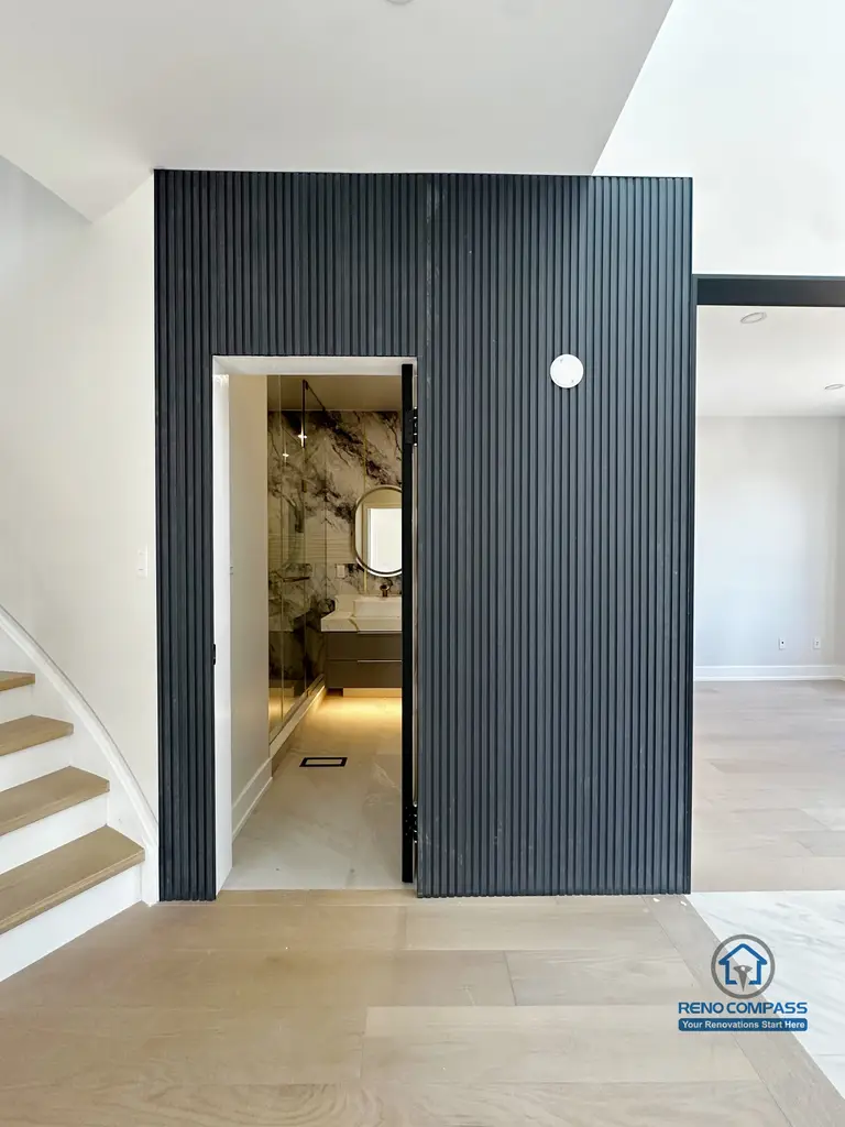 This Markham interior renovation highlights a bold vertical slat feature wall that defines circulation while adding architectural depth to the space. The recessed powder room entrance is seamlessly integrated into the wall, creating a clean and intentional transition between public and private areas. Natural wood flooring, soft neutral tones, and carefully planned lighting work together to enhance spatial clarity and visual balance. The result is a modern interior that feels structured, refined, and thoughtfully detailed.