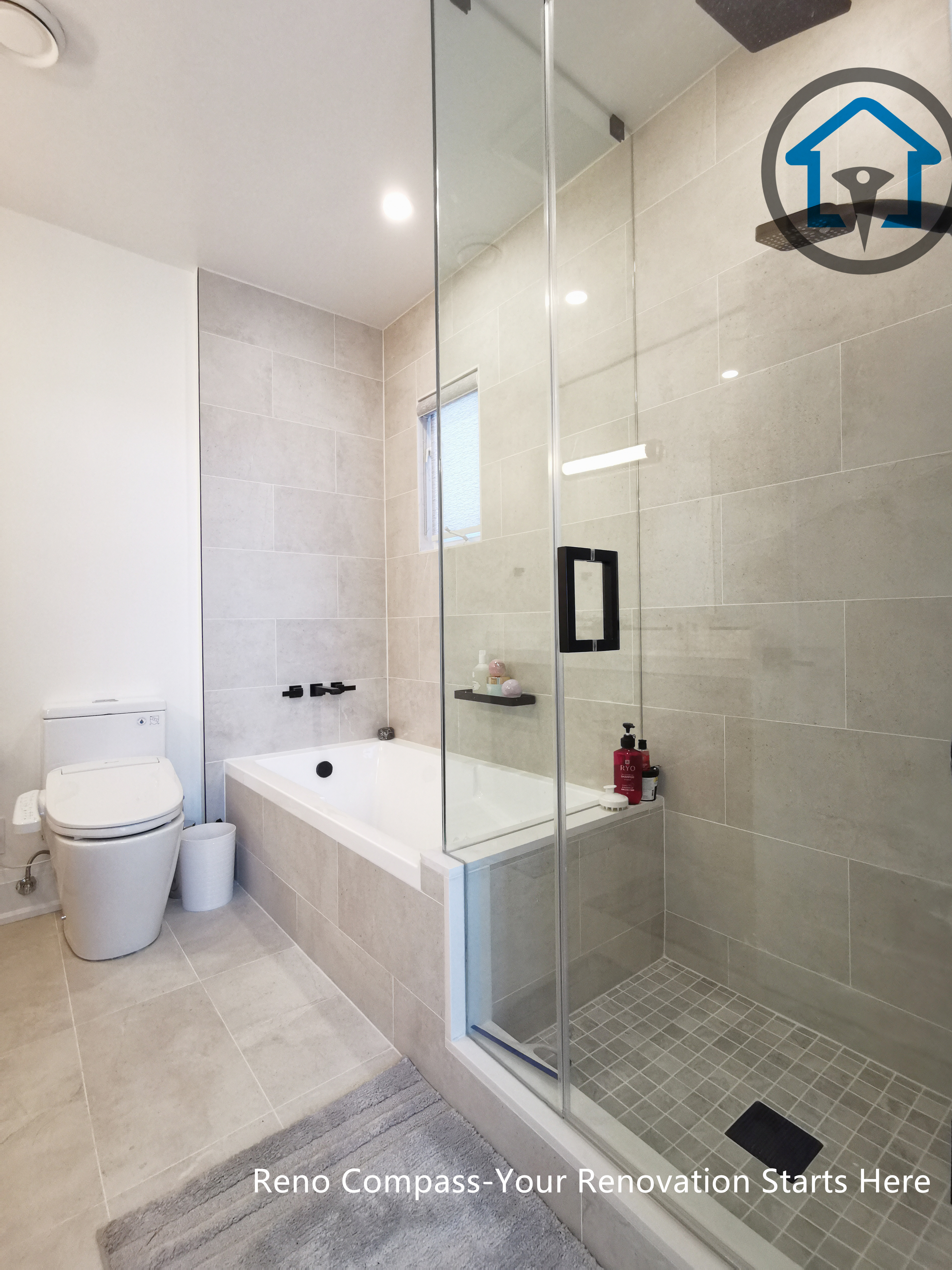 This North York bathroom renovation showcases a clean and functional layout featuring a built-in bathtub, a glass-enclosed shower, and soft neutral tile finishes. Matte black fixtures add contrast while the compact window improves natural light and ventilation, creating a bright and comfortable bathroom completed by a Toronto renovation company focused on quality workmanship and practical design.