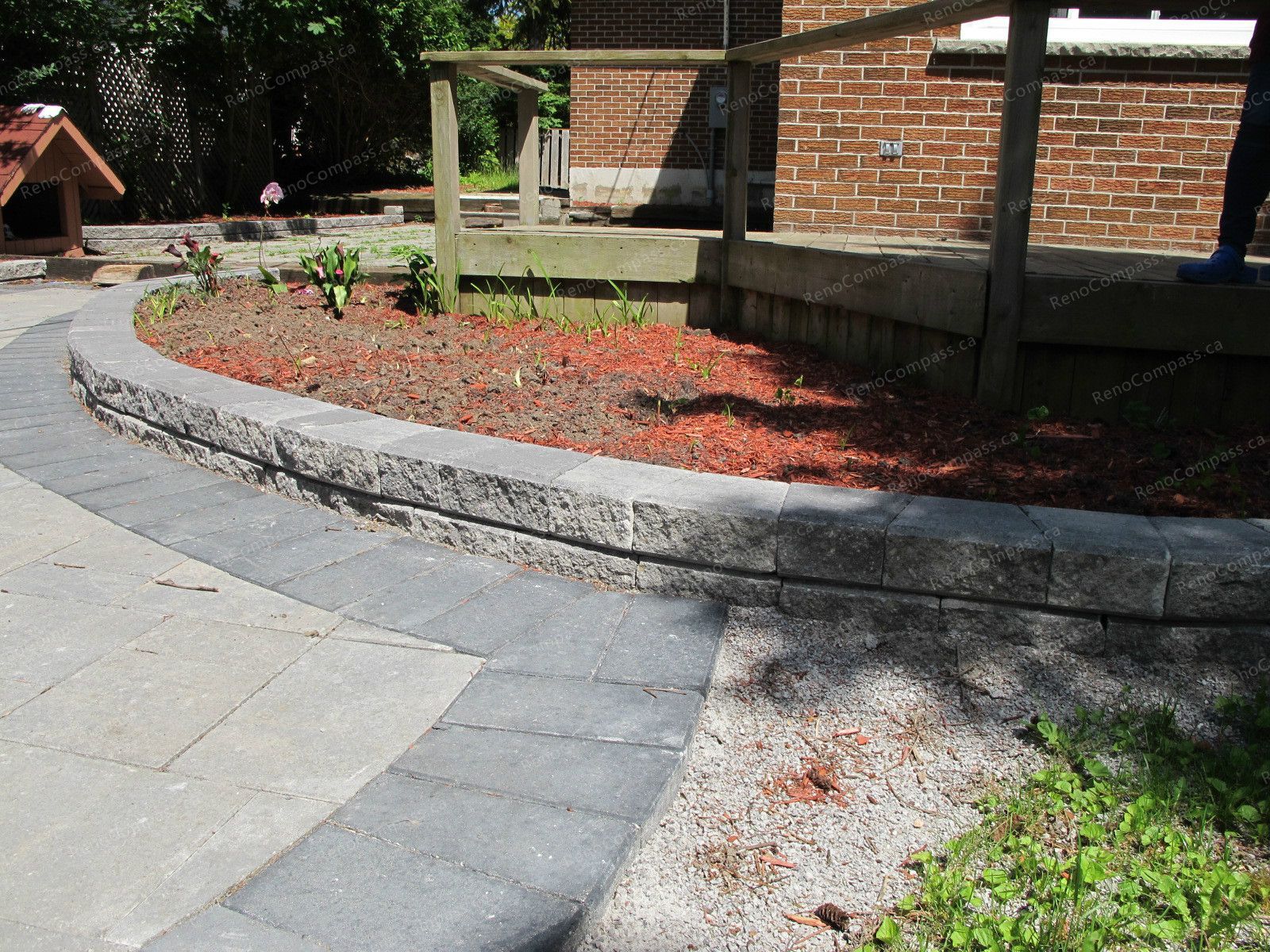 This Markham landscaping project showcases a custom-built garden bed constructed with durable interlock stone. The curved interlock edging creates a clean and structured flower bed layout while enhancing the overall backyard design. Filled with fresh mulch and ready for planting, the raised flower bed adds depth and visual interest to the outdoor space. Completed by Reno Compass Inc., this project highlights professional craftsmanship in interlock landscaping and garden design, delivering a low-maintenance and elegant outdoor environment for homeowners.