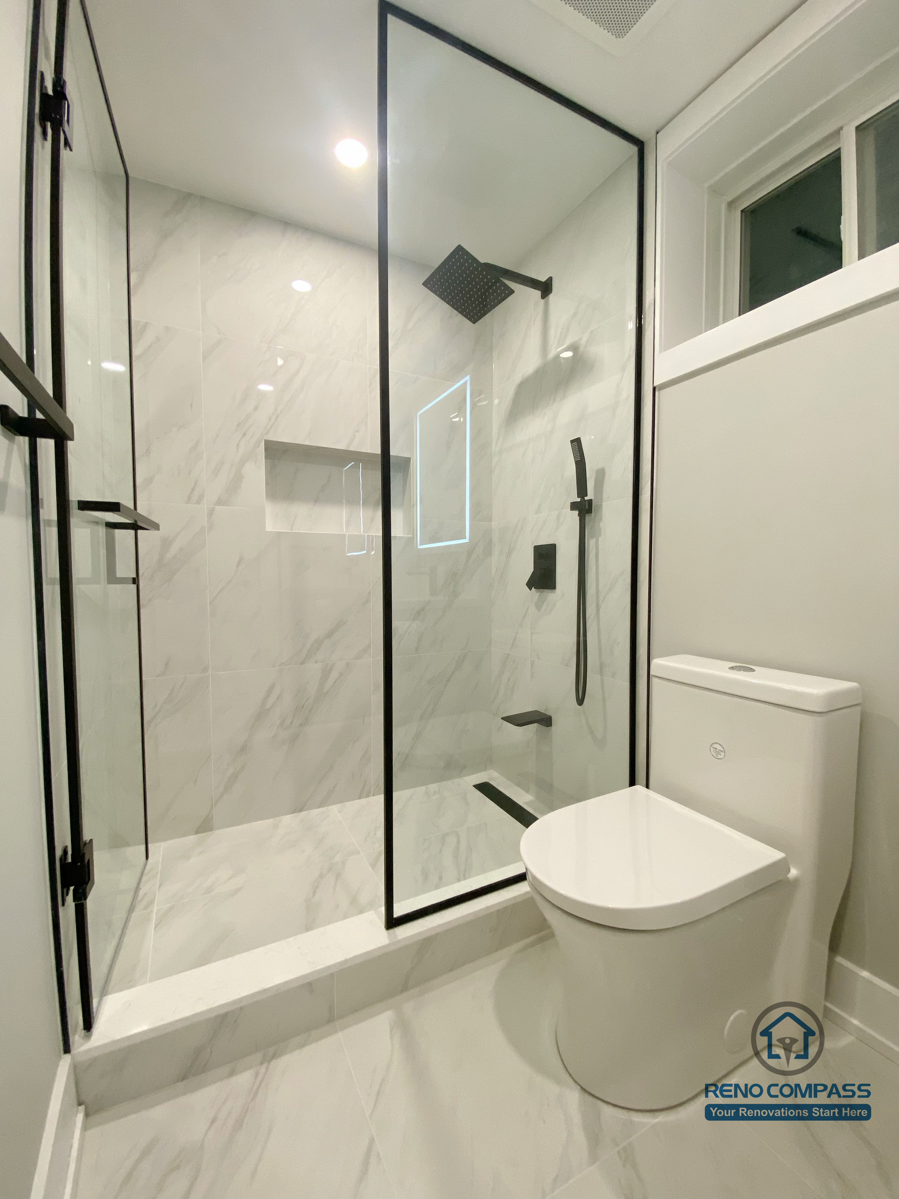 This Aurora basement renovation features a modern full bathroom with a glass-enclosed shower, marble-look wall and floor tiles, a floating vanity, and an LED-lit mirror. The compact layout is designed for efficiency and comfort, combining clean lines with durable finishes suitable for basement use. Completed by a Toronto renovation company, this basement bathroom renovation reflects thoughtful space planning and contemporary bathroom design standards.