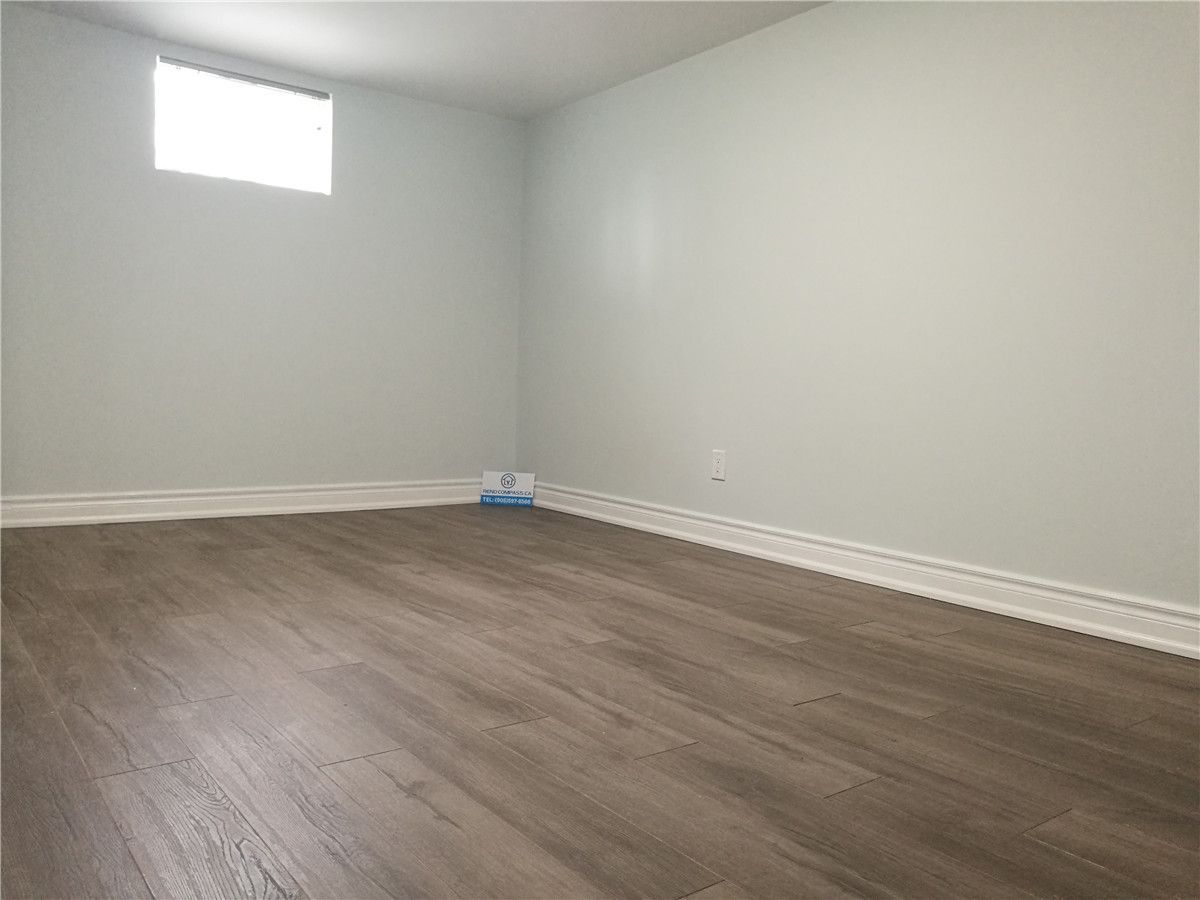 Finished interior space from a Pickering basement renovation project featuring new wood-look flooring, clean white walls, baseboard trim, and a bright window for natural light. This simple and functional room upgrade improves comfort and usability, completed by a professional Toronto renovation company.