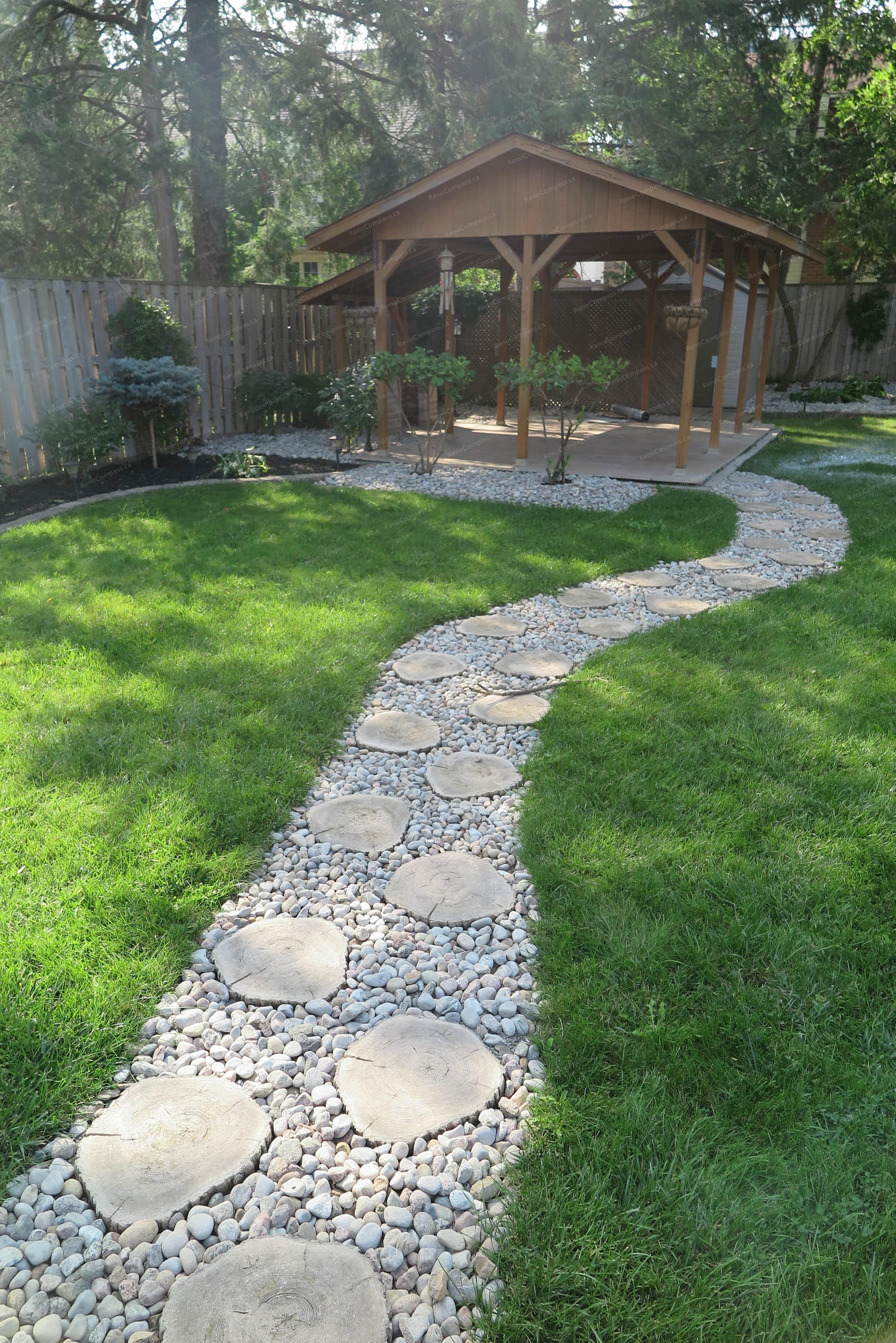This image features a North York landscaping renovation highlighting a curved stepping stone pathway set in decorative gravel, leading through a manicured lawn toward a wooden pavilion. The pathway improves circulation, visual flow, and outdoor usability while maintaining a natural, low-maintenance design. Completed by a Toronto Renovation Company specializing in custom backyard landscaping and pathway construction.