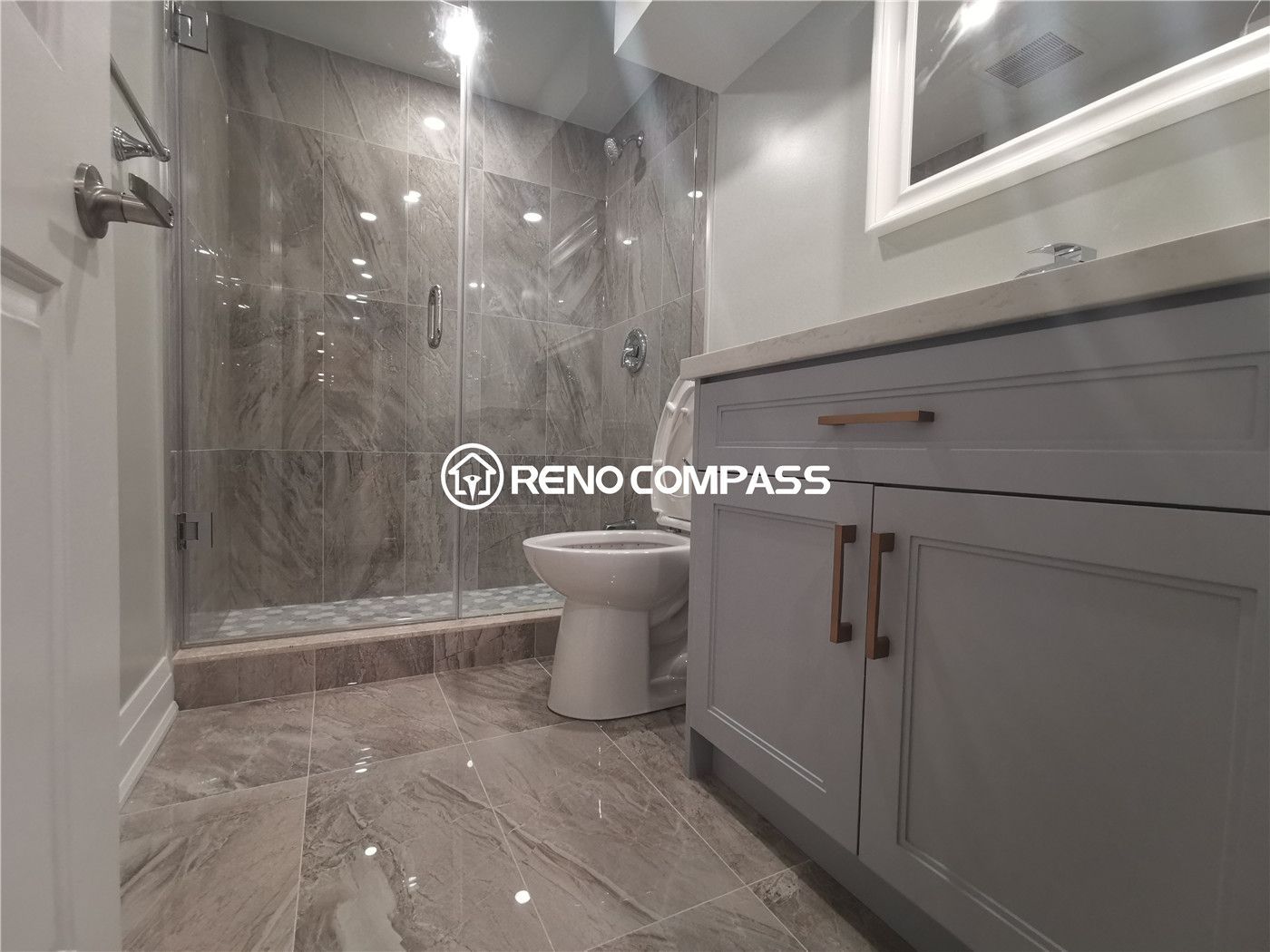 This Markham basement renovation showcases a fully upgraded bathroom featuring a glass-enclosed walk-in shower, marble-look porcelain tiles, modern vanity with quartz countertop, and sleek chrome fixtures. The combination of large-format floor tiles and detailed shower mosaic flooring enhances durability, water resistance, and visual appeal. A clean neutral color palette and contemporary finishes create a bright and functional basement bathroom environment. Completed by a professional Toronto renovation company, this project highlights expert tile installation, quality plumbing fixtures, and modern basement bathroom design tailored for homes in the Greater Toronto Area.