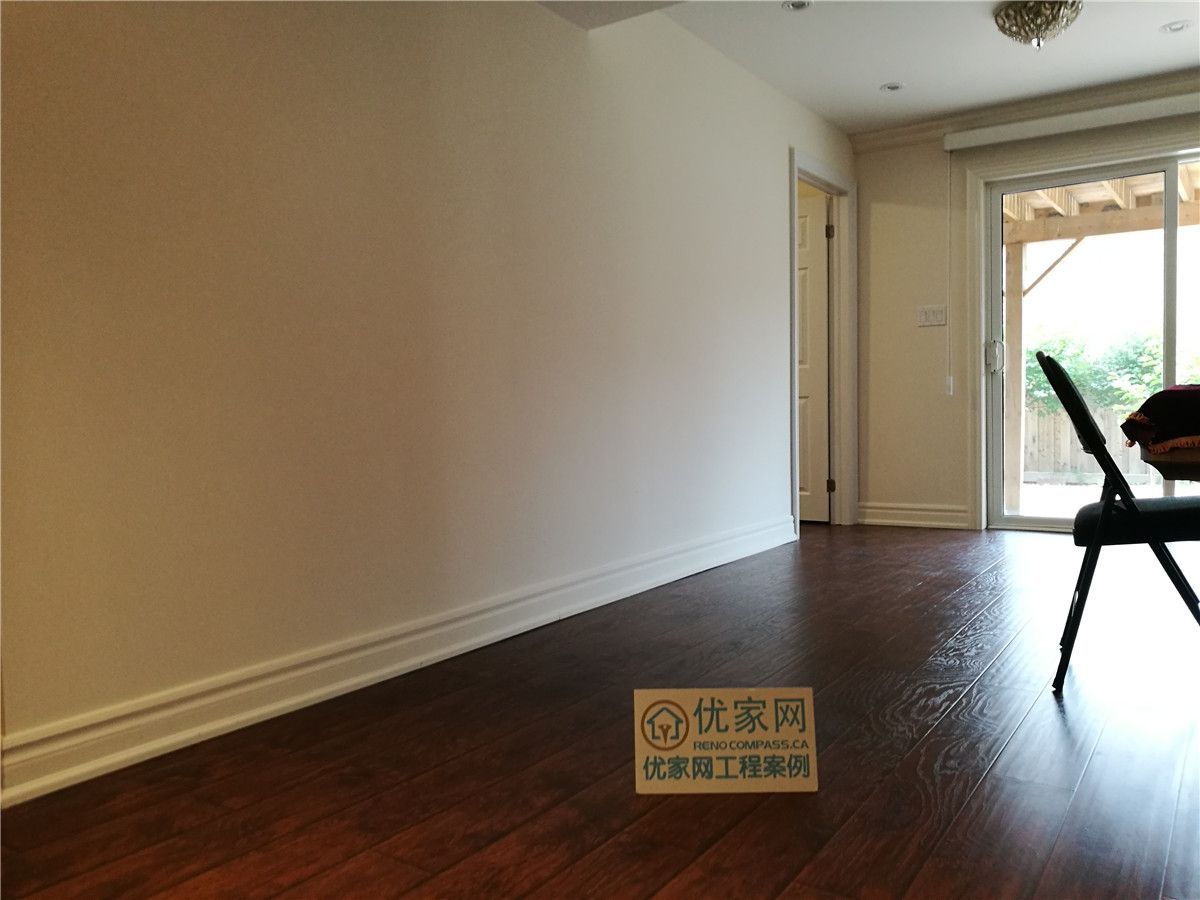 Completed living area as part of a Toronto interior renovation project, featuring dark-toned flooring, clean wall finishes, and natural light from sliding patio doors. The updated space offers a simple, functional layout with improved brightness and a warm, modern residential feel.