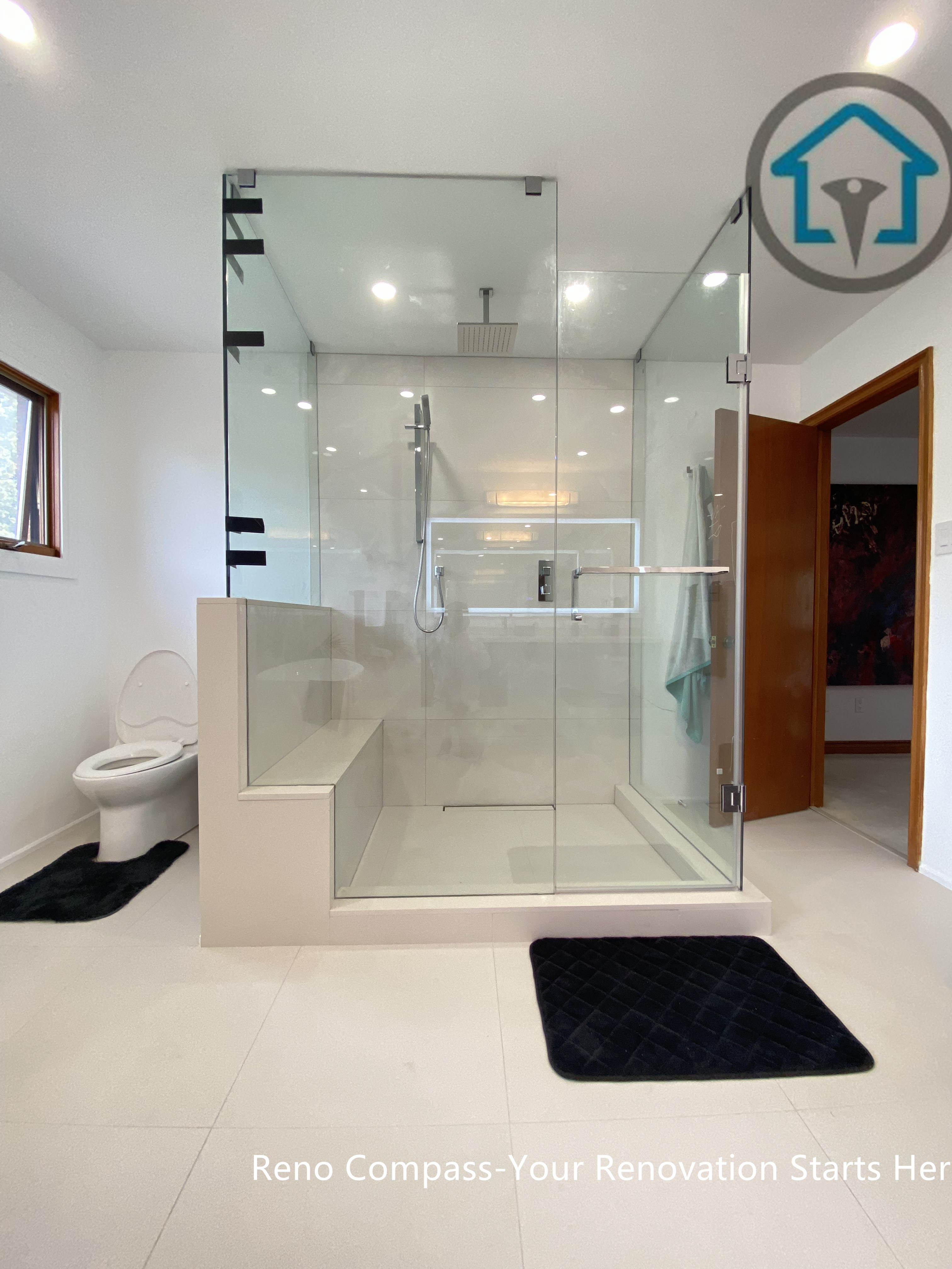 Modern bathroom renovation in Brampton showcasing a frameless glass walk-in shower with a built-in bench and curbless entry. The symmetrical layout, large-format tiles, and recessed ceiling lights enhance visual balance and spatial openness. Completed by a trusted Toronto renovation company, this shower design focuses on accessibility, safety, and long-term everyday functionality.