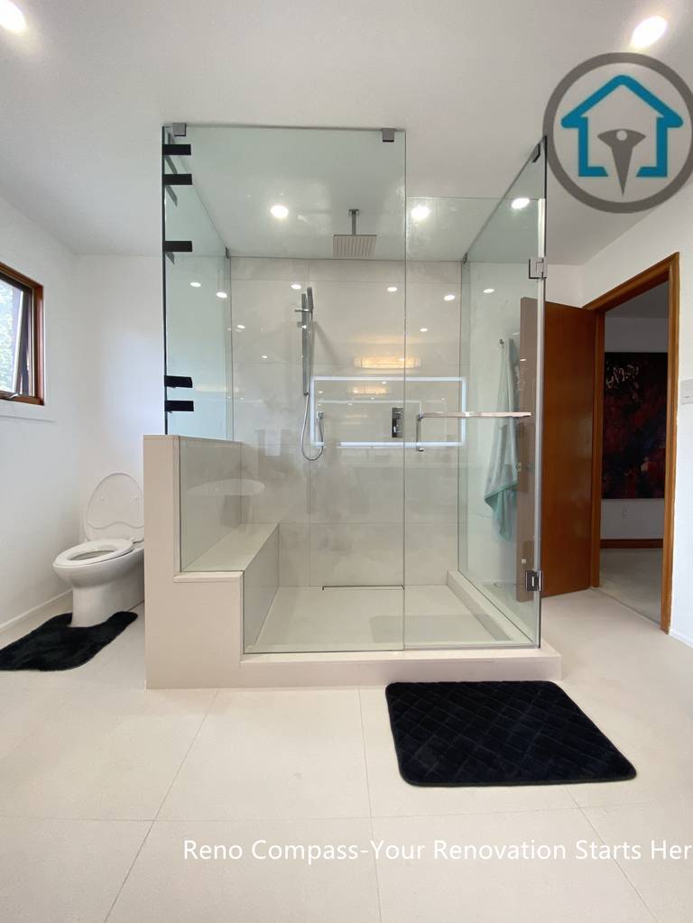 Modern bathroom renovation in Brampton showcasing a frameless glass walk-in shower with a built-in bench and curbless entry. The symmetrical layout, large-format tiles, and recessed ceiling lights enhance visual balance and spatial openness. Completed by a trusted Toronto renovation company, this shower design focuses on accessibility, safety, and long-term everyday functionality.