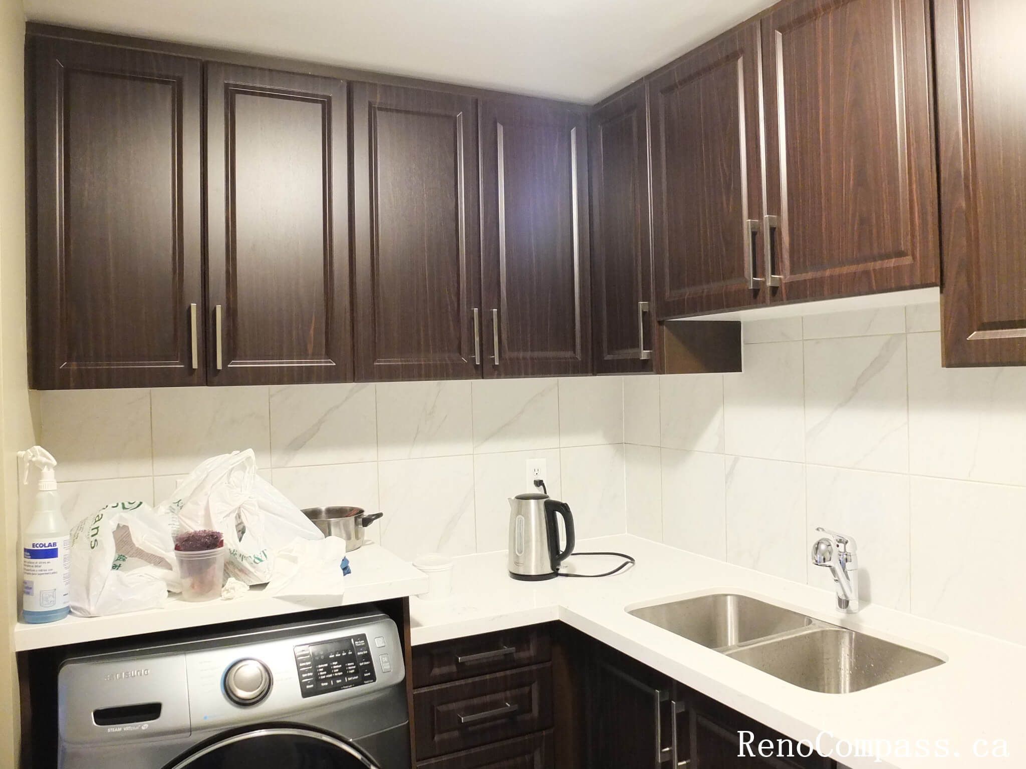 Close-up of a modern L-shaped kitchen featuring rich espresso shaker-style cabinets, a durable white quartz countertop, and a double undermount stainless steel sink. Expertly installed by Reno Compass in Mississauga.