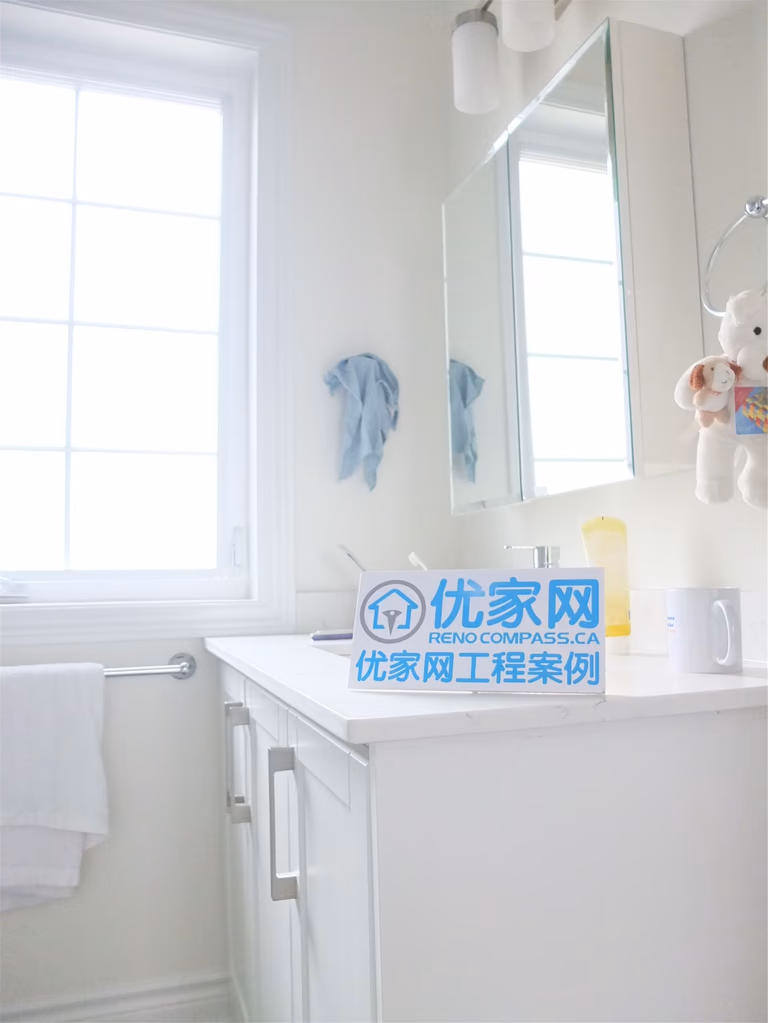 Bright bathroom space from a Scarborough home addition project featuring a modern white vanity cabinet, mirror storage, and large window for natural light. The renovation improves functionality and comfort while maintaining a clean and contemporary interior design.