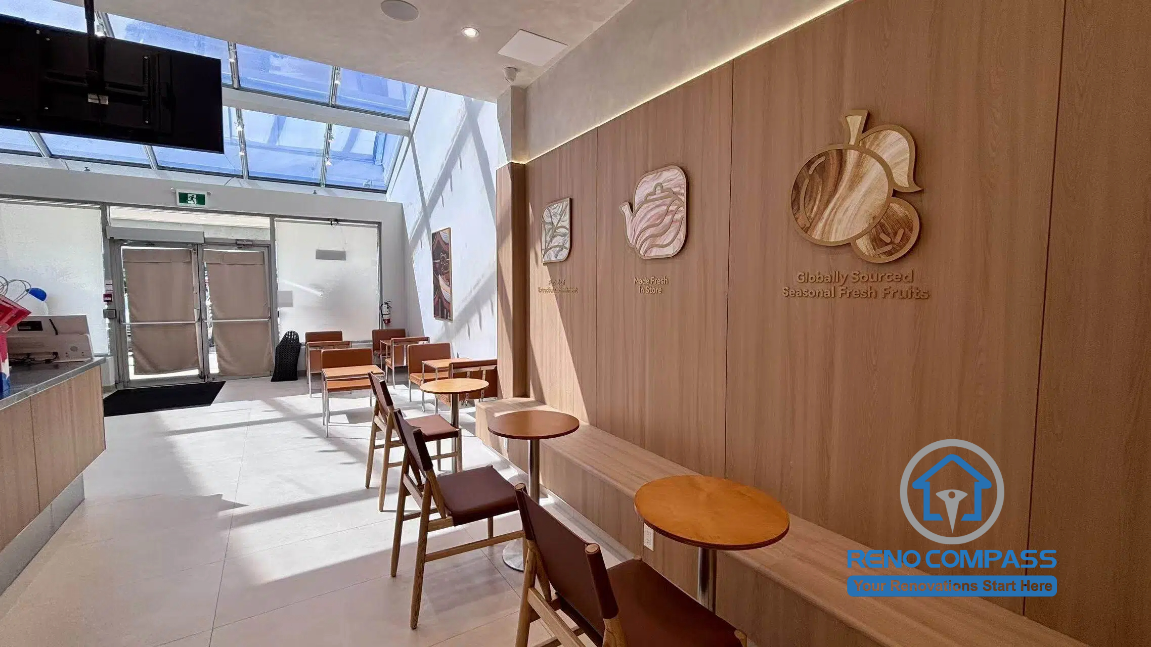 Completed TEABYDO bubble tea shop renovation in Richmond Hill featuring a modern café seating area with custom wood wall finishes, integrated bench seating, skylight ceiling, minimalist customer tables, and warm commercial interior design. This bright and welcoming commercial renovation project was completed by Reno Compass serving Richmond Hill, Toronto, and the GTA.