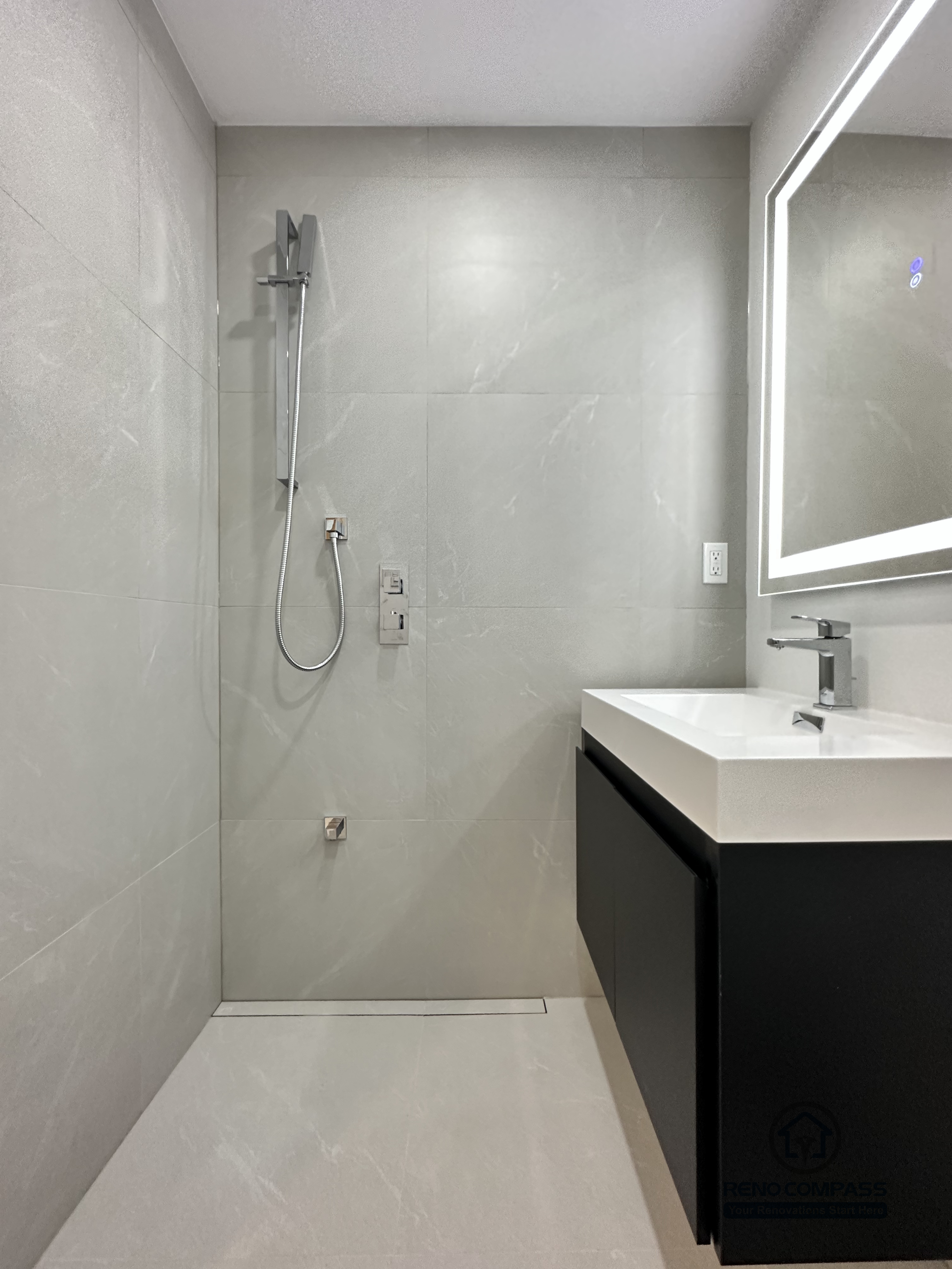This image highlights a barrier-free walk-in shower designed for a pet-friendly accessible bathroom renovation in Brampton. The curbless shower entry, linear floor drain, and large-format wall tiles create a seamless, easy-to-clean space that is safe for both pets and homeowners. A handheld shower system allows flexible use for pet bathing, while the open layout improves accessibility and mobility. This modern, functional design reflects the expertise of a professional Toronto Renovation Company specializing in accessible and pet-conscious bathroom renovations.