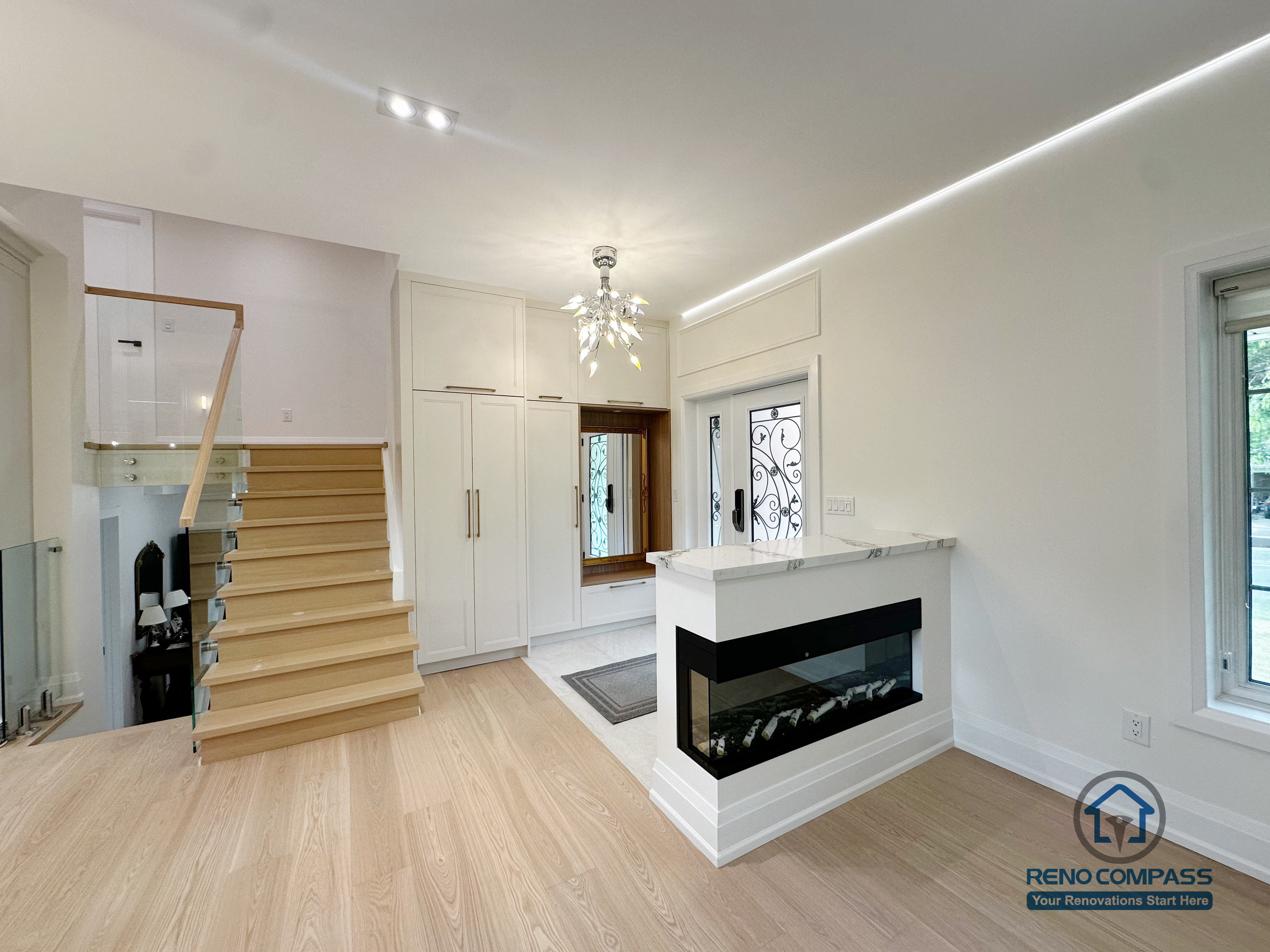 A beautifully redesigned transition space featuring a modern glass staircase, a sleek built-in fireplace, and warm engineered hardwood flooring. Clean lines, soft lighting, and thoughtful storage create a bright and welcoming entry into the main living area.
通透感十足的楼梯设计搭配内嵌式壁炉，温润木纹地板让整个空间更明亮、舒适。灯光与动线经过重新规划，使玄关与客厅之间的过渡更自然、质感更高级。
