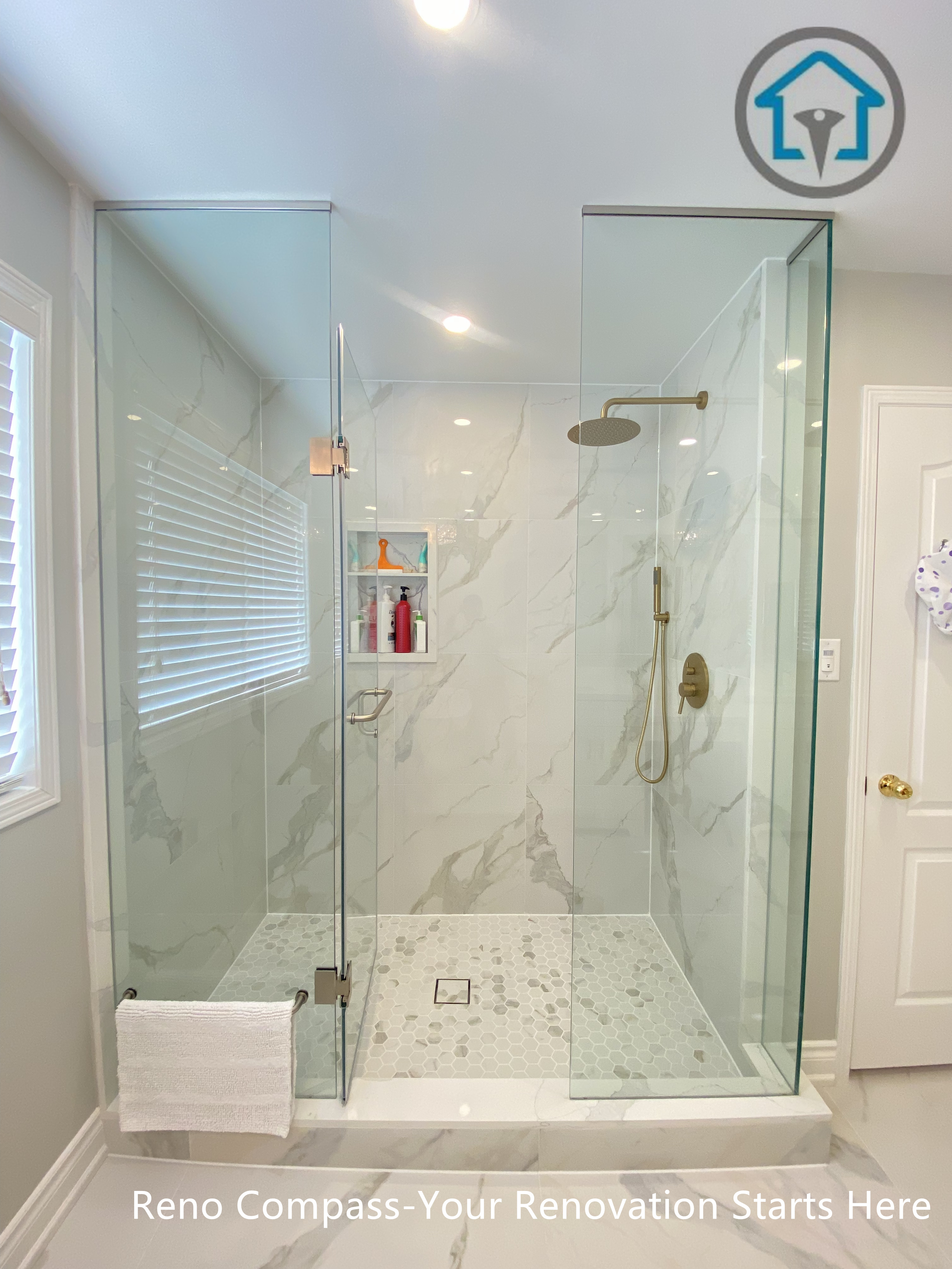 This Mississauga bathroom renovation features a spacious walk-in shower enclosed with frameless clear glass panels to enhance openness and natural light. Large-format marble-look wall tiles are paired with a mosaic tile shower floor for slip resistance and visual contrast. Gold-tone shower fixtures add warmth and elegance, while a built-in wall niche provides functional storage without disrupting the clean layout. The shower design prioritizes comfort, drainage efficiency, and long-term durability through precise detailing and quality materials.