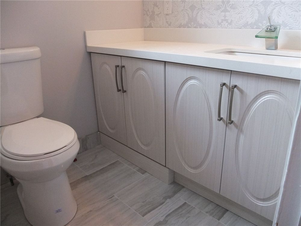 This North York bathroom renovation showcases a custom vanity cabinet with a quartz countertop, integrated sink, and modern hardware paired with a new toilet installation. The combination of durable flooring, bright finishes, and functional storage enhances both comfort and practicality. Completed by a professional Toronto renovation company, the design creates a clean, modern bathroom space suitable for everyday living.