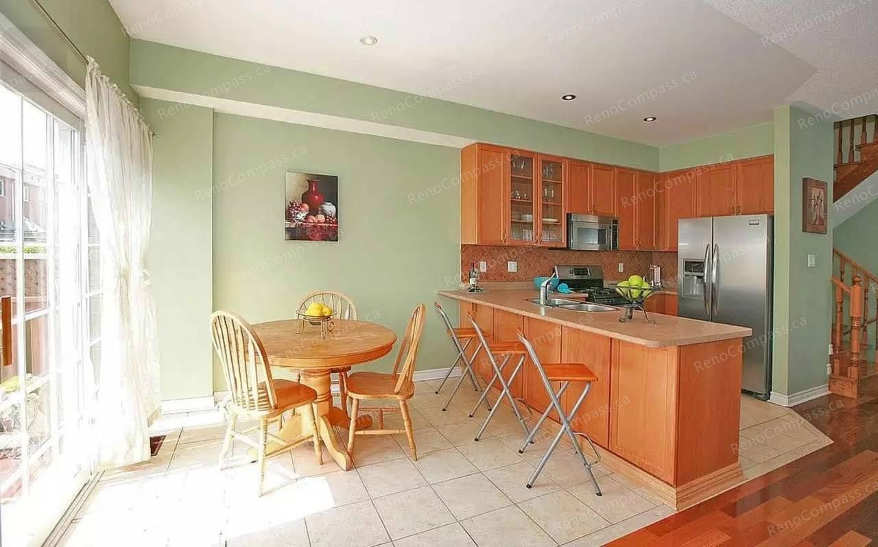 This Vaughan kitchen renovation showcases a bright open-concept layout with warm wood cabinetry, a functional breakfast island, and a cozy dining area filled with natural light. Completed by a trusted Toronto renovation company, the upgraded kitchen improves workflow, storage, and everyday comfort while creating a welcoming space for family living and entertaining.