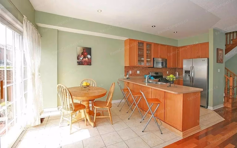 This Vaughan kitchen renovation showcases a bright open-concept layout with warm wood cabinetry, a functional breakfast island, and a cozy dining area filled with natural light. Completed by a trusted Toronto renovation company, the upgraded kitchen improves workflow, storage, and everyday comfort while creating a welcoming space for family living and entertaining.