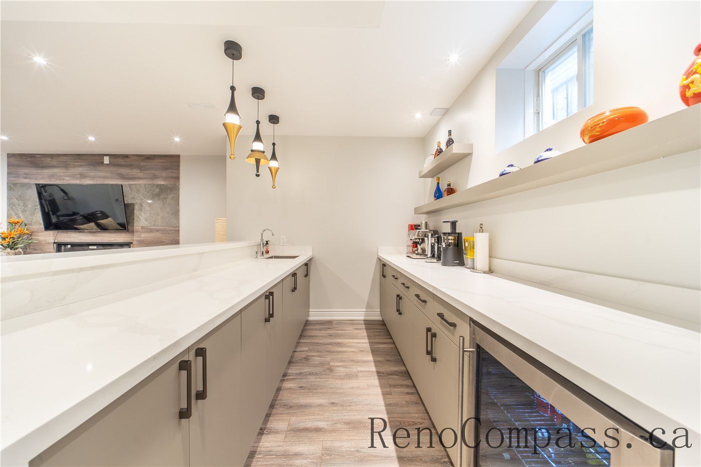 This Richmond Hill entire house interior renovation showcases a modern kitchen and prep area with custom cabinetry, quartz countertops, and sleek pendant lighting. The spacious layout includes a built-in beverage fridge, open shelving, and extended counter space designed for entertaining and everyday convenience. Completed by a trusted Toronto renovation company, this kitchen renovation blends functionality, storage, and contemporary style to enhance the overall home living experience.
