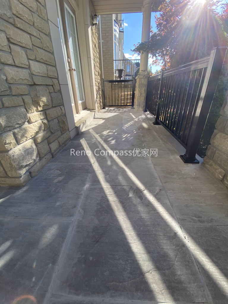 This image features a natural stone interlocking walkway along the side entrance of a North York home. The stone pavers are precisely installed to create a smooth, level walking surface that integrates seamlessly with the home’s stone exterior and metal railing. Proper spacing, alignment, and surface preparation ensure durability, drainage performance, and safe year-round use. Designed as part of a complete driveway interlocking project, this walkway enhances accessibility while maintaining a cohesive outdoor design. Completed by a Toronto interlocking and landscaping contractor, the project demonstrates careful craftsmanship and attention to functional detailing.