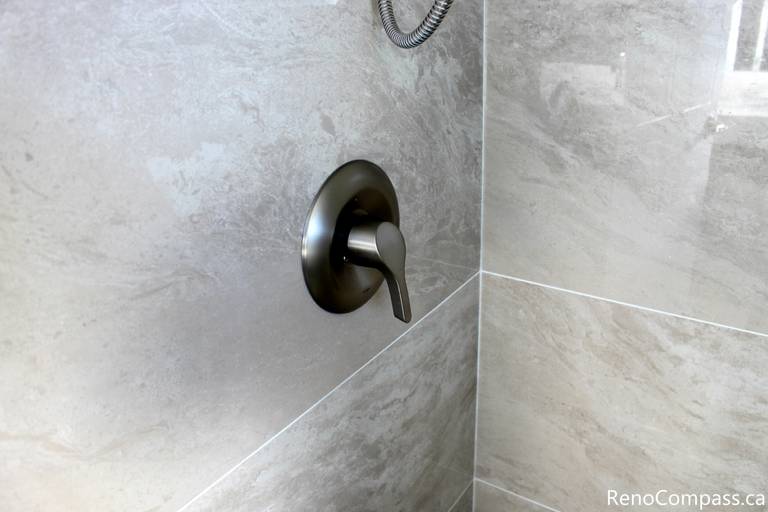 This Mississauga bathroom renovation presents an overall view of the shower area, featuring a glass enclosure and tiled walls. The layout emphasizes space efficiency, natural light, and a clean modern design suitable for everyday residential use.