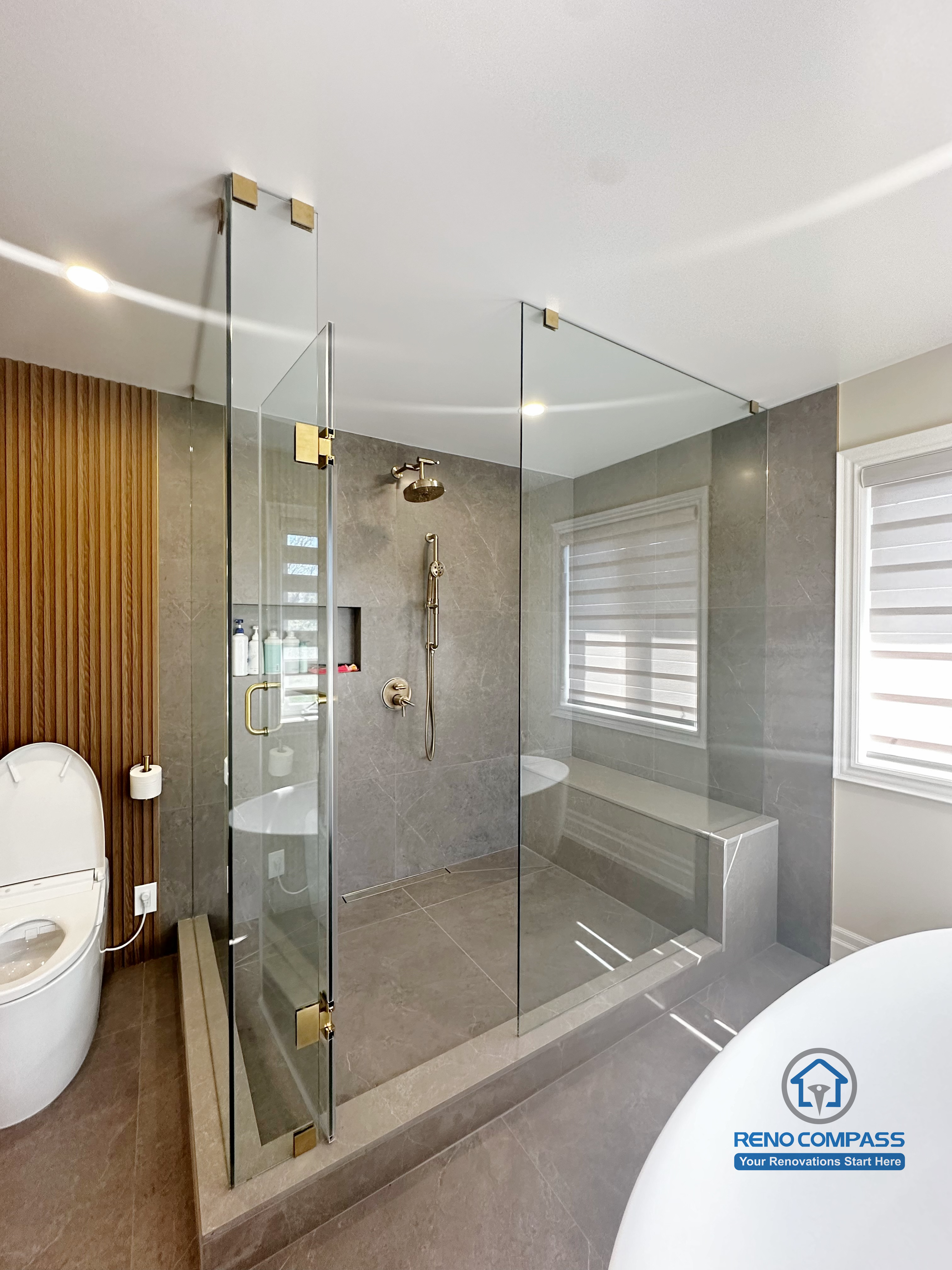 This bathroom renovation in North York combines a frameless glass shower enclosure with a freestanding tub and soft natural light. The spacious layout and refined material selection create a luxury spa-like experience.
